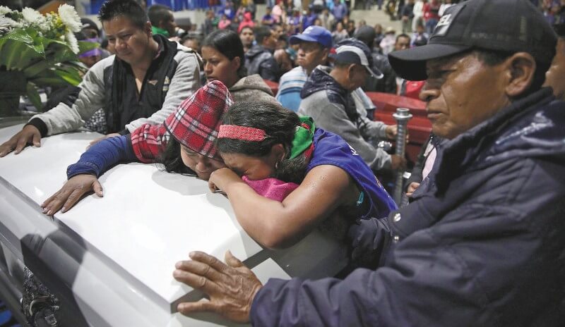 Familiares y amigos de uno de los líderes indígenas asesinados lloran sobre su féretro en el sepelio, en Corinto (Cauca). / AFP
