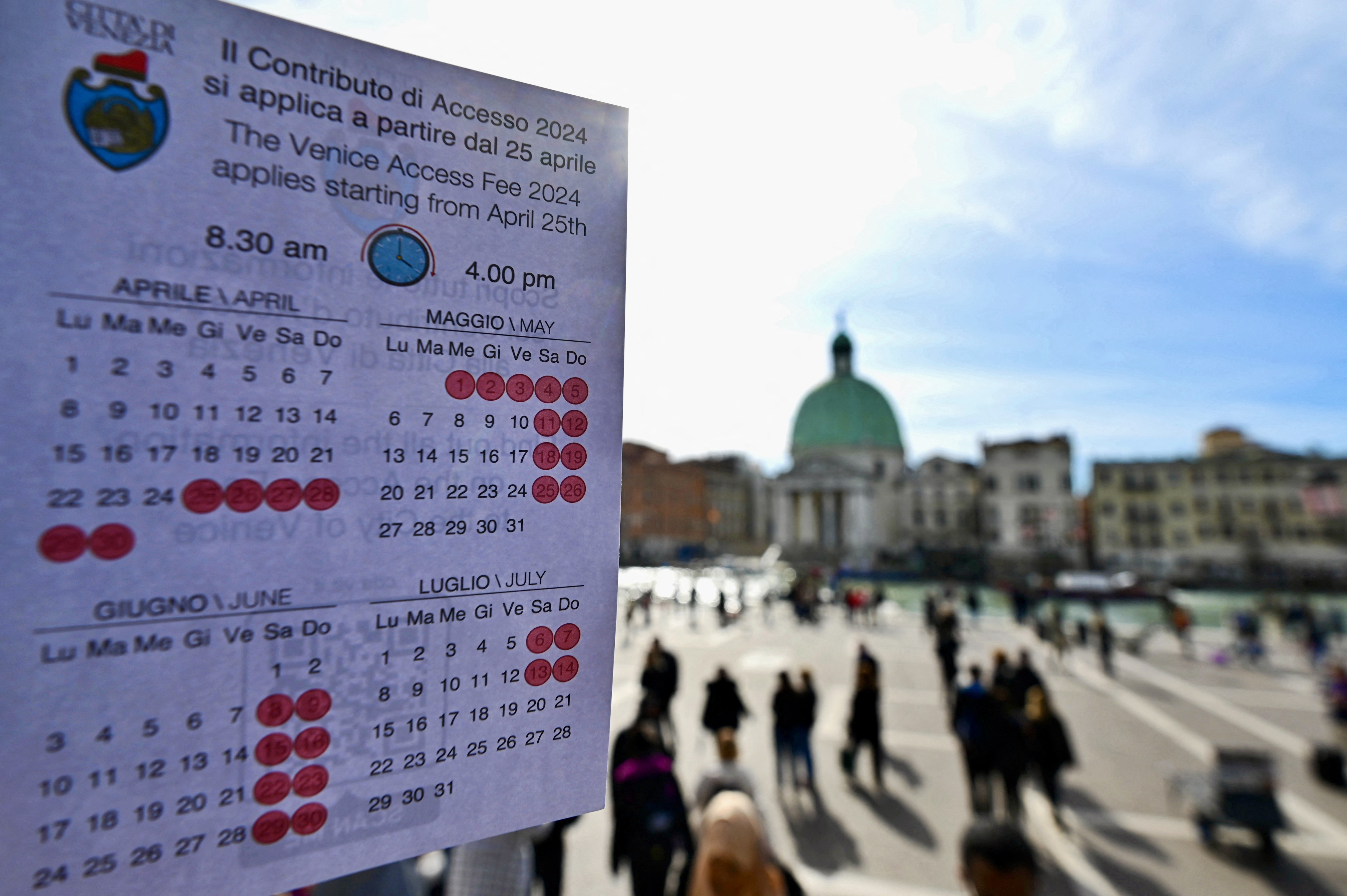A person shows a calendar of the paying days to visit Venice, on April 19, 2024 in front of Santa Lucia train station in Venice.