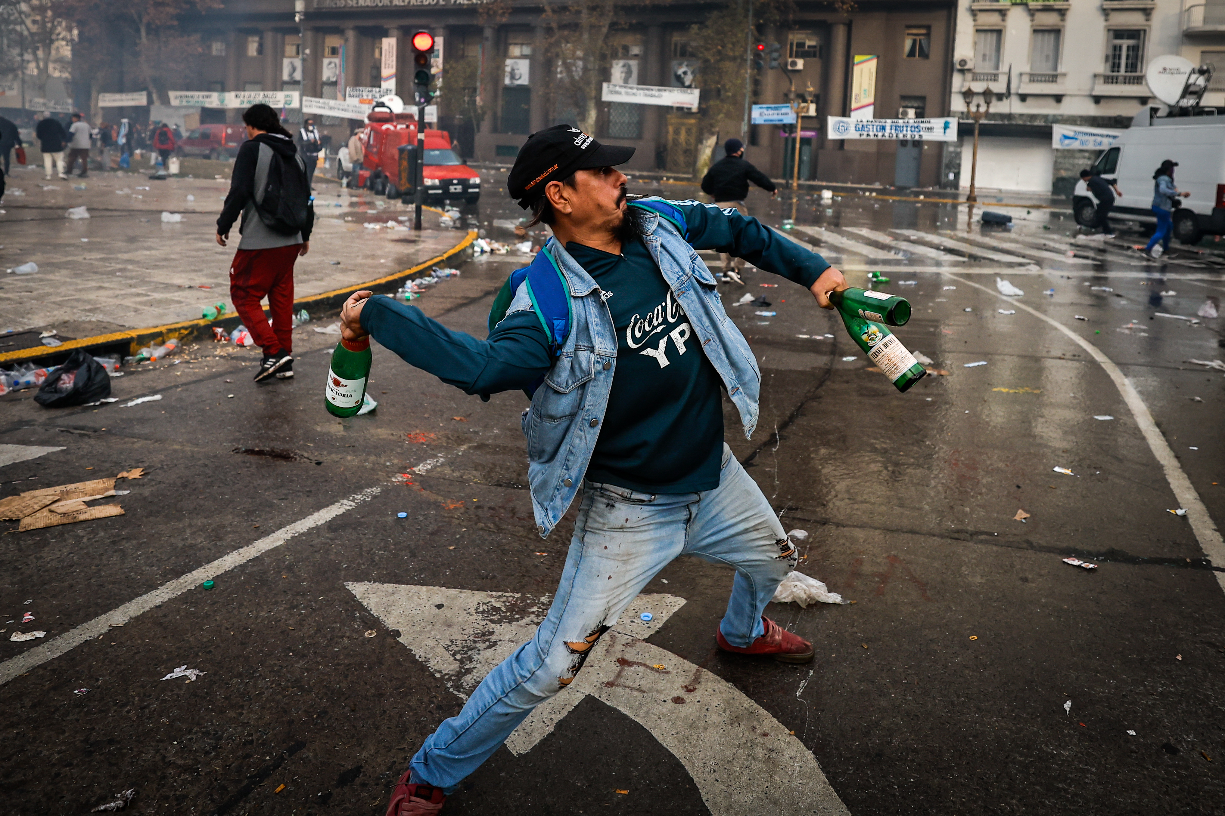 AME3498. BUENOS AIRES (ARGENTINA), 12/06/2024.- Un hombre lanza botellas de vidrio durante enfrentamientos entre la policía y personas que protestan a las afueras del senado durante un debate este miércoles, en Buenos Aires (Argentina). Manifestantes y policías protagonizan un choque este miércoles a las puertas del Senado de Argentina mientras la cámara legislativa debate la ley de Bases, el proyecto estrella del Gobierno, con el que el presidente Javier Milei pretende implementar un paquete de reformas económicas de gran calado. EFE/ Juan Ignacio Roncoroni