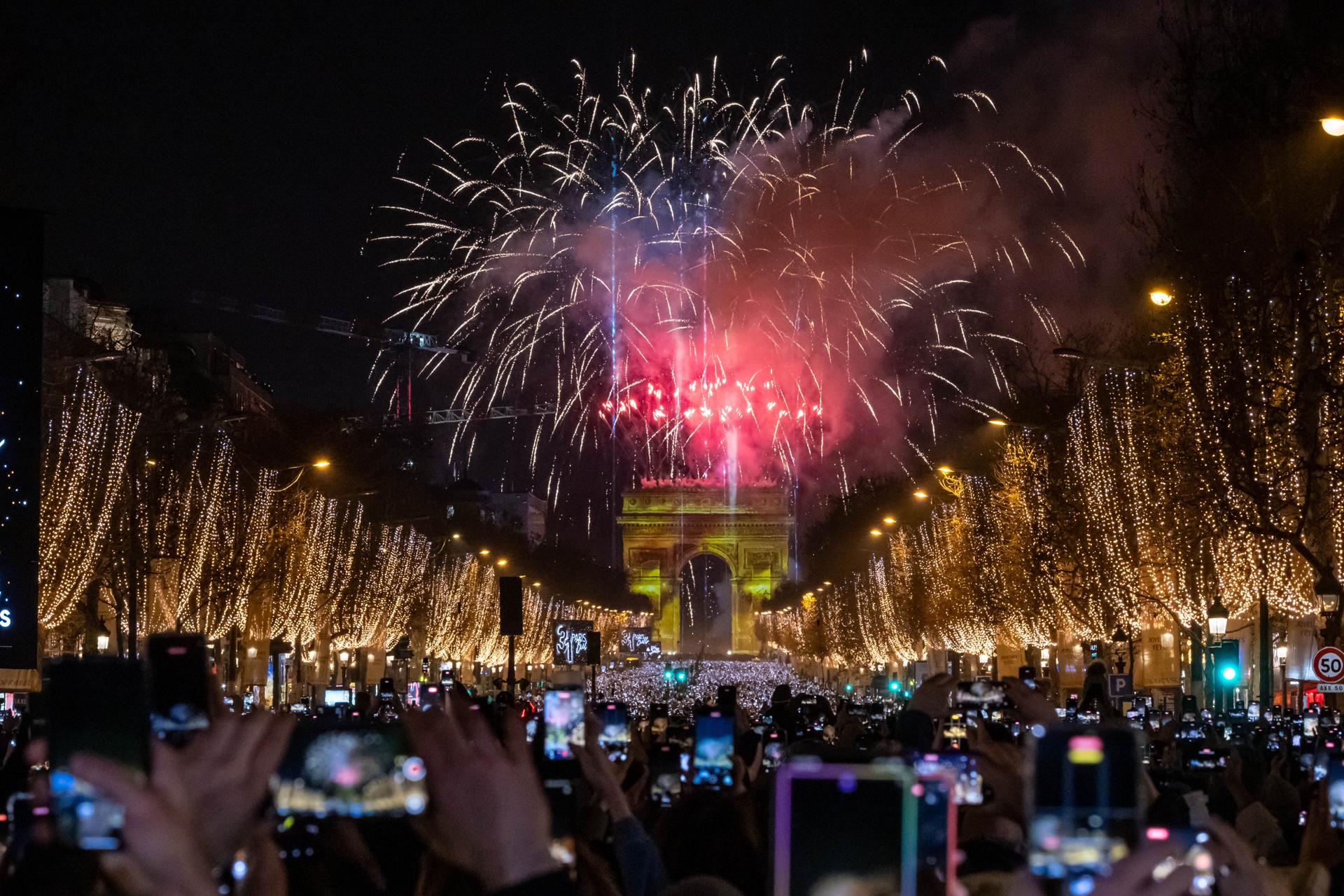 PARIS (France), 31/12/2025.- Revelers look at a light and fireworks show displayed on the Arc de Triomphe to celebrate the New Year 2026 on the Champs-Elysees avenue in Paris, France, 31 December 2025. (Francia) EFE/EPA/CHRISTOPHE PETIT TESSON