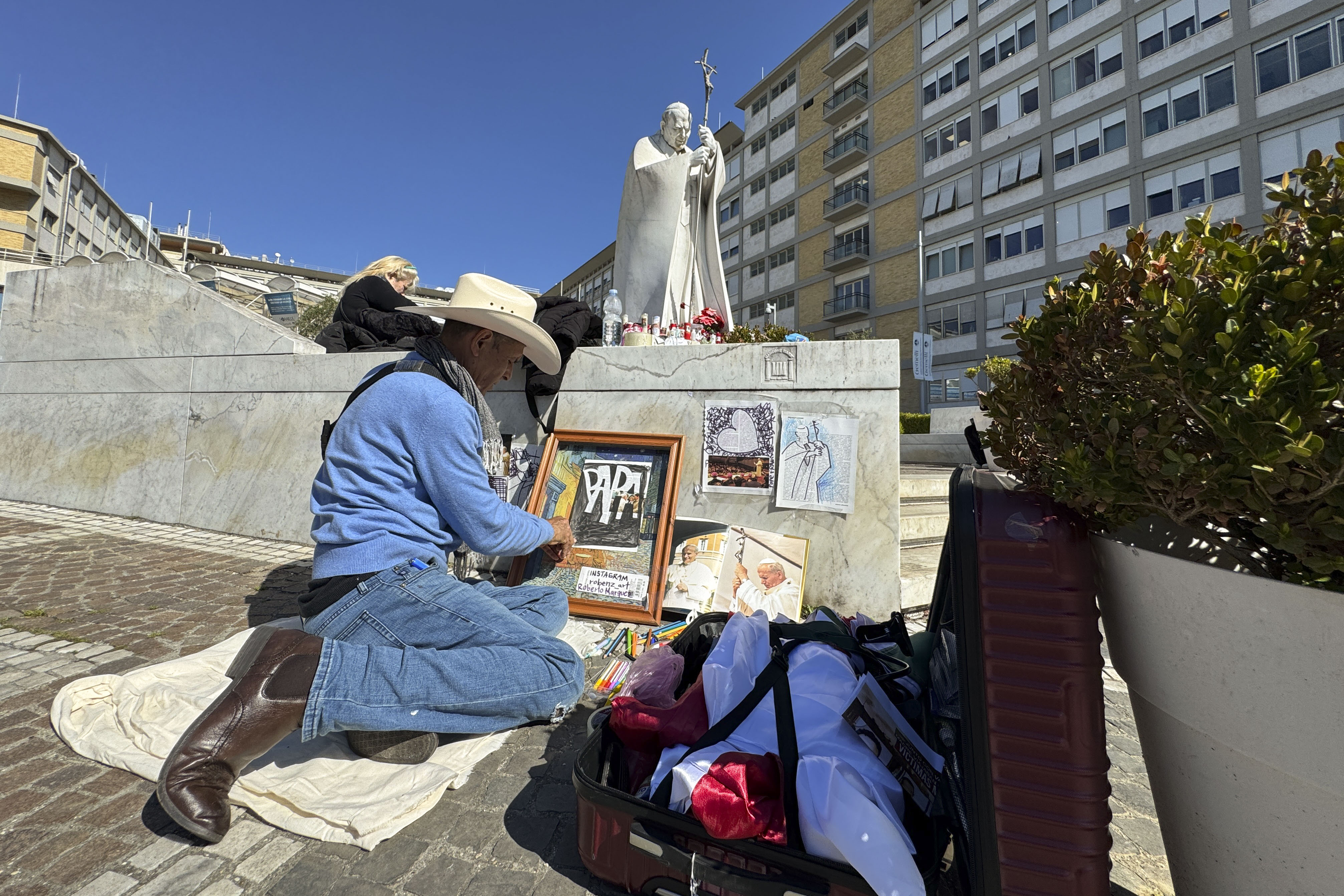 CIUDAD DEL VATICANO, 03/03/2025.- Un artista dibuja ante la escultura del papa Juan Pablo II, a las puertas del Hospital Gemelli donde permanece ingresado el papa. El papa Francisco descansó toda la noche, se despertó, desayunó y comenzó el tratamiento diario en el décimo octavo día de hospitalización y, en cuanto a la neumonía bilateral, "la situación es estable" y sigue "una evolución natural", informaron fuentes vaticanas. Según las mismas fuentes, el papa ha dormido bien toda la noche y, como ya ocurrió el domingo, no está sometido a ventilación mecánica y se le está administrando oxígeno mediante cánulas nasales. EFE/Daniel Cáceres
