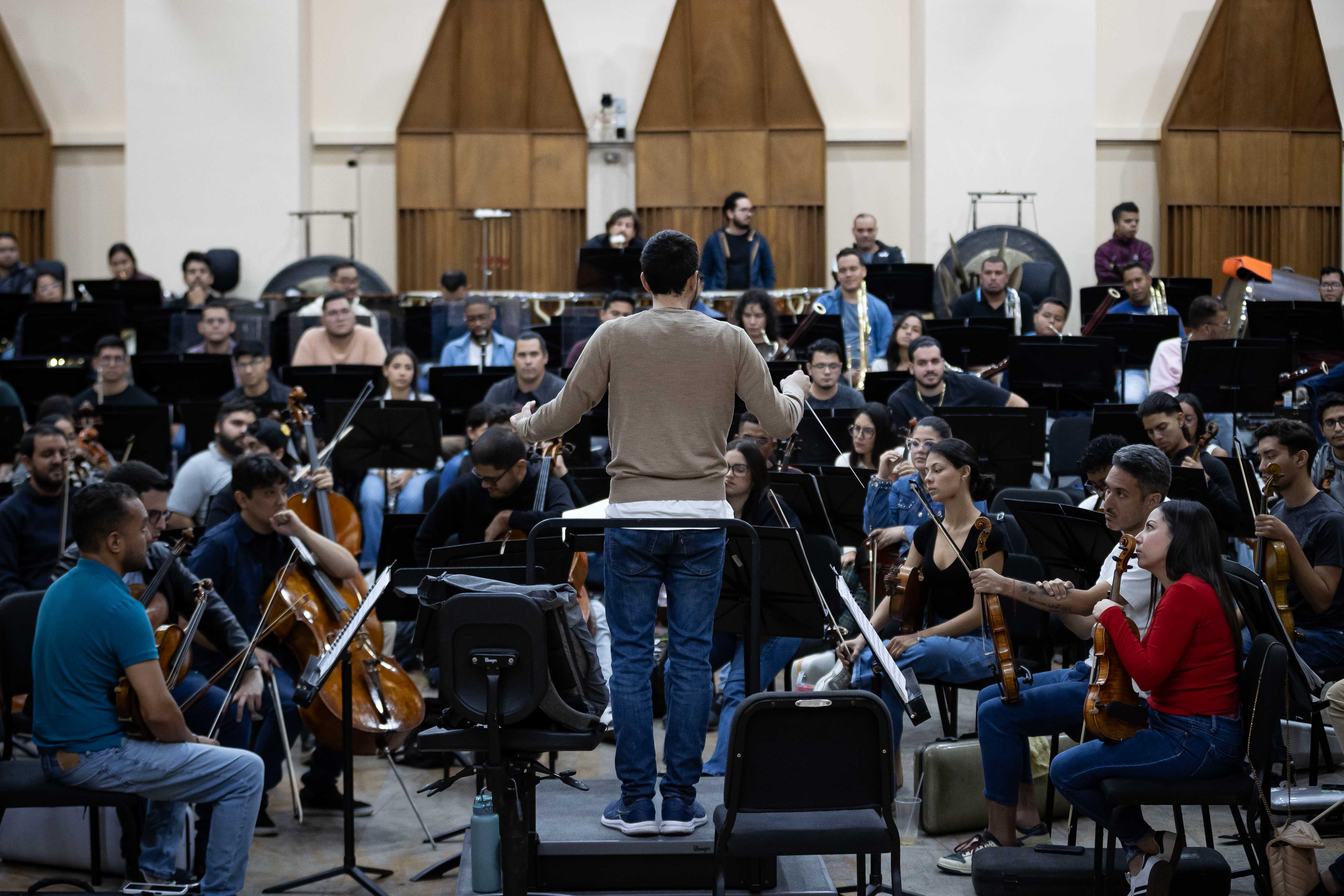 AME7375. CARACAS (VENEZUELA), 26/12/2024.- Fotografía del 17 de diciembre de 2024 del director académico musical Andrés David Ascanio Abreu (c), durante una práctica con la Orquesta Sinfónica Simón Bolívar de Venezuela en Caracas (Venezuela). El Sistema de Orquestas y Coros Juveniles e Infantiles de Venezuela celebrará el 50 aniversario de su fundación una gira por Europa de la mano del maestro Gustavo Dudamel, que incluirá encuentros académicos con niños y jóvenes, así como conciertos conjuntos en siete ciudades, dijo en una entrevista con EFE Eduardo Méndez, director ejecutivo de la agrupación musical. EFE/ Ronald Peña R.
