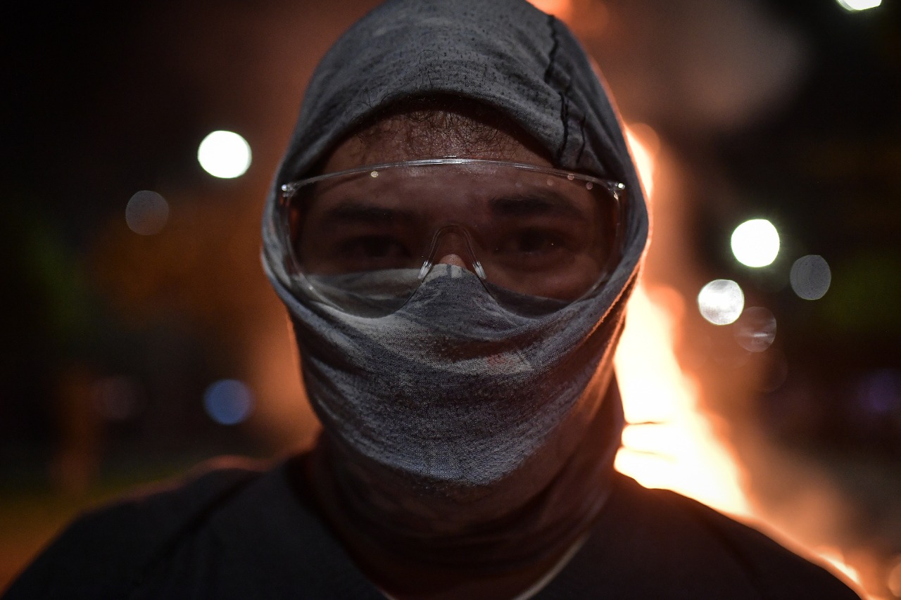 Un hombre con la cara tapada y gafas mirando a la cámara.