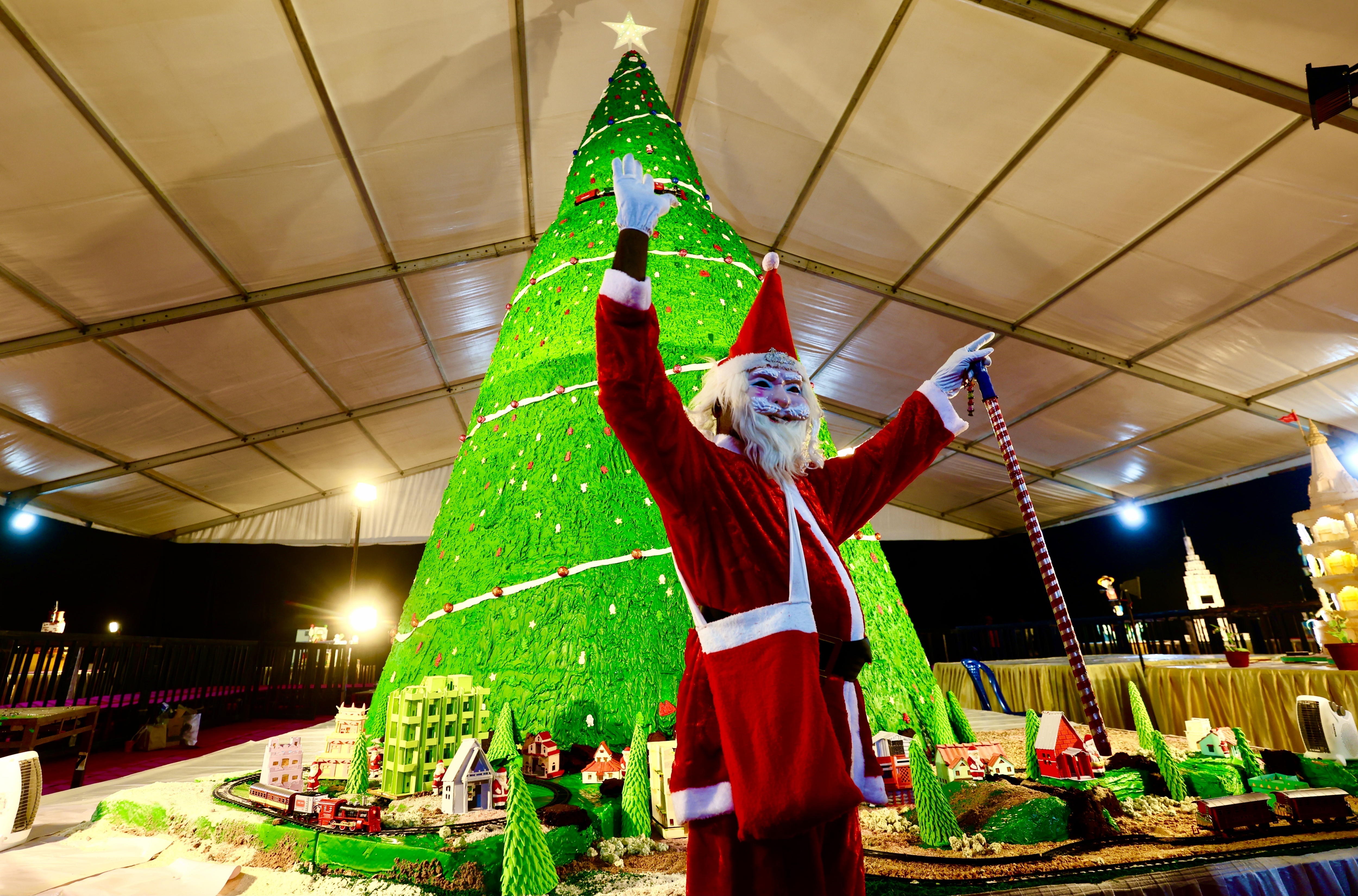 Bangalore (India), 12/12/2024.- A person dressed in a Santa costume poses in front of sugar cake models displayed during a media preview ahead of the official opening of the 50th annual Cake Show ahead of Christmas, in Bangalore, India, 12 December 2024. The exhibition runs from 13 December to 01 January 2025. EFE/EPA/JAGADEESH NV