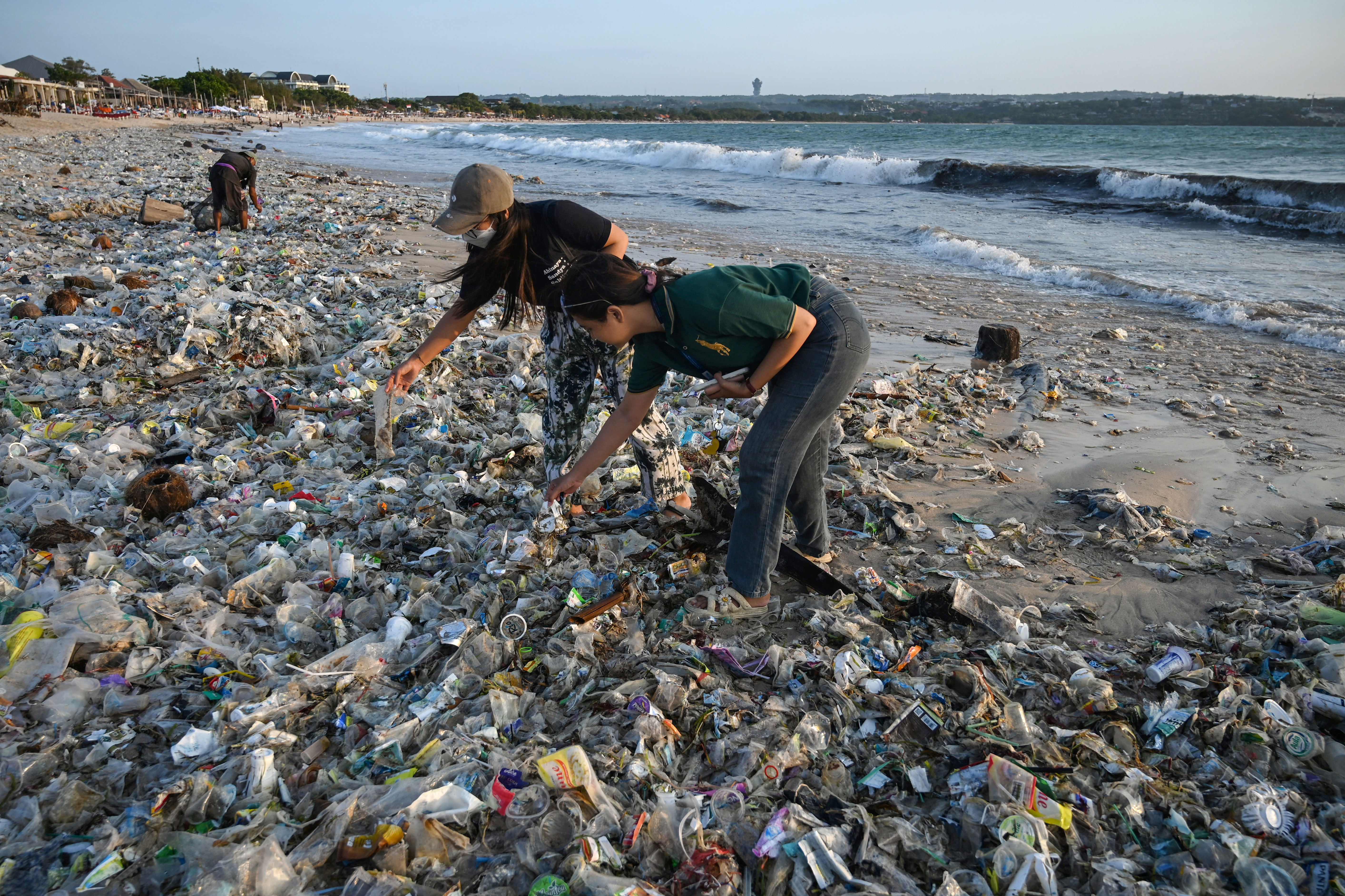 (FILES) People look through plastic and other debris washed ashore at Kedonganan Beach near Denpasar on Indonesia's resort island of Bali on March 19, 2024.