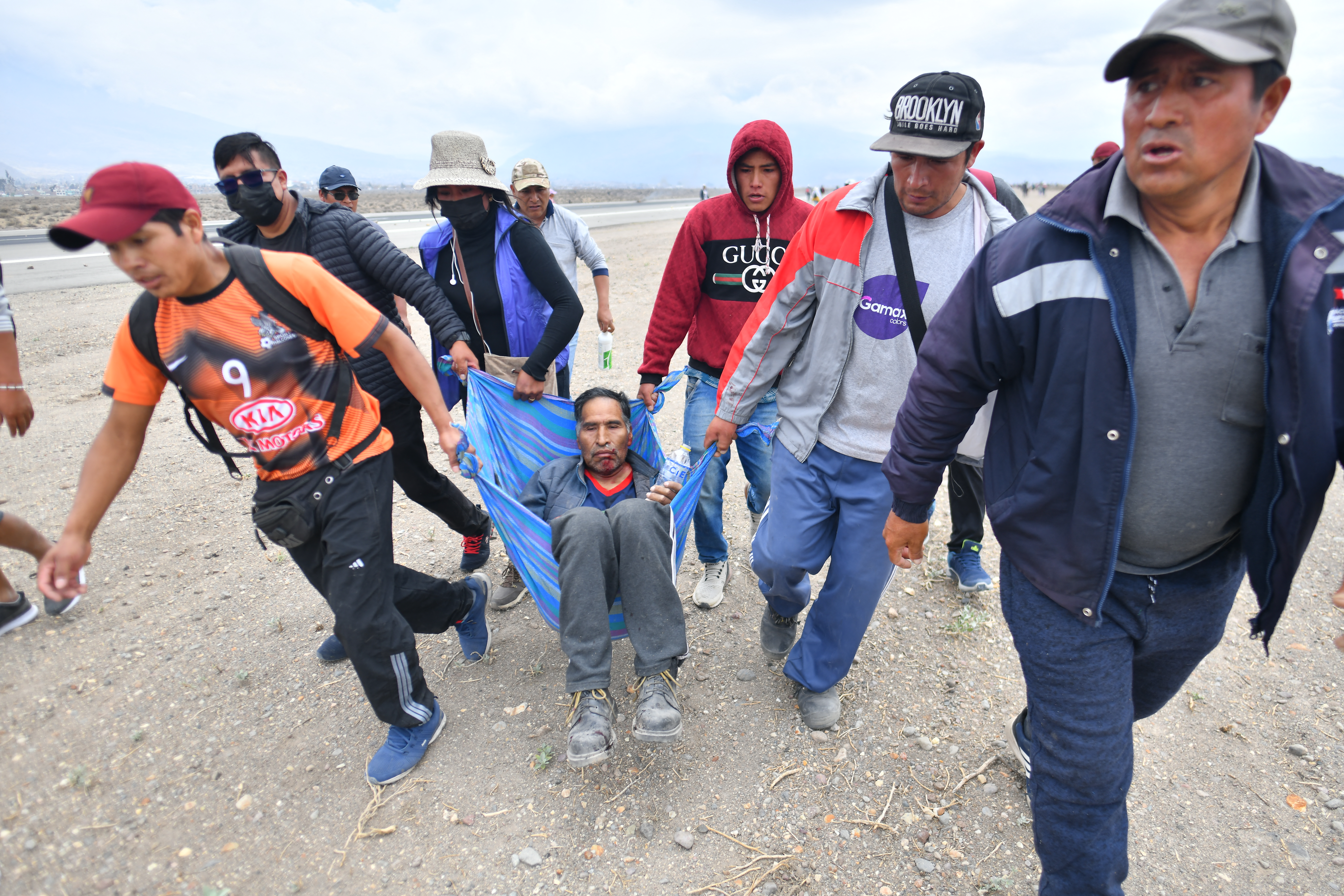 Los manifestantes llevan a un hombre herido mientras toman el aeropuerto.