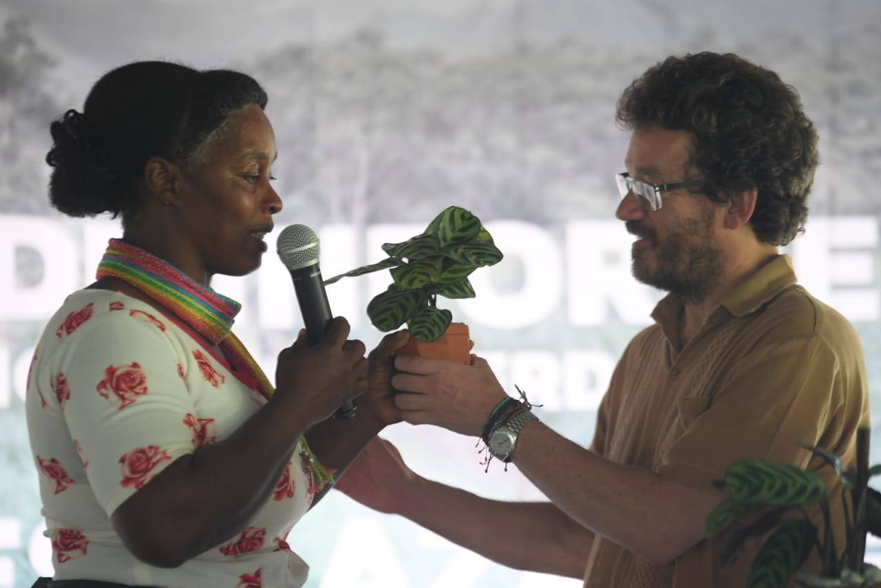 Pie de foto: Nohelia Paz, de la comunidad de Cacarica, le entrega una planta al comisionado Alejandro Valencia que simboliza la importancia de la biodiversidad para sus comunidades.