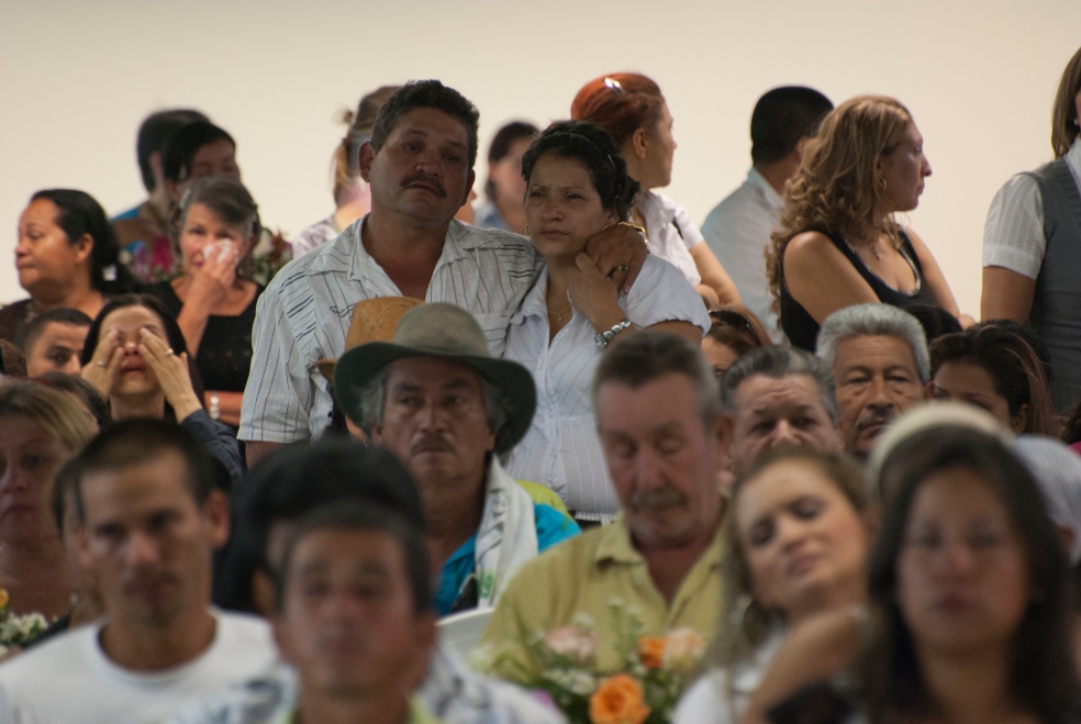 Una pareja está de pie al fondo de una multitud de personas.