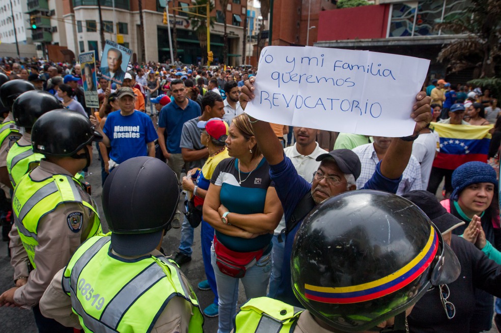 Un grupo de personas protestó frente a miembros de la Policía Nacional Bolivariana (PNB) en Caracas. / EFE
