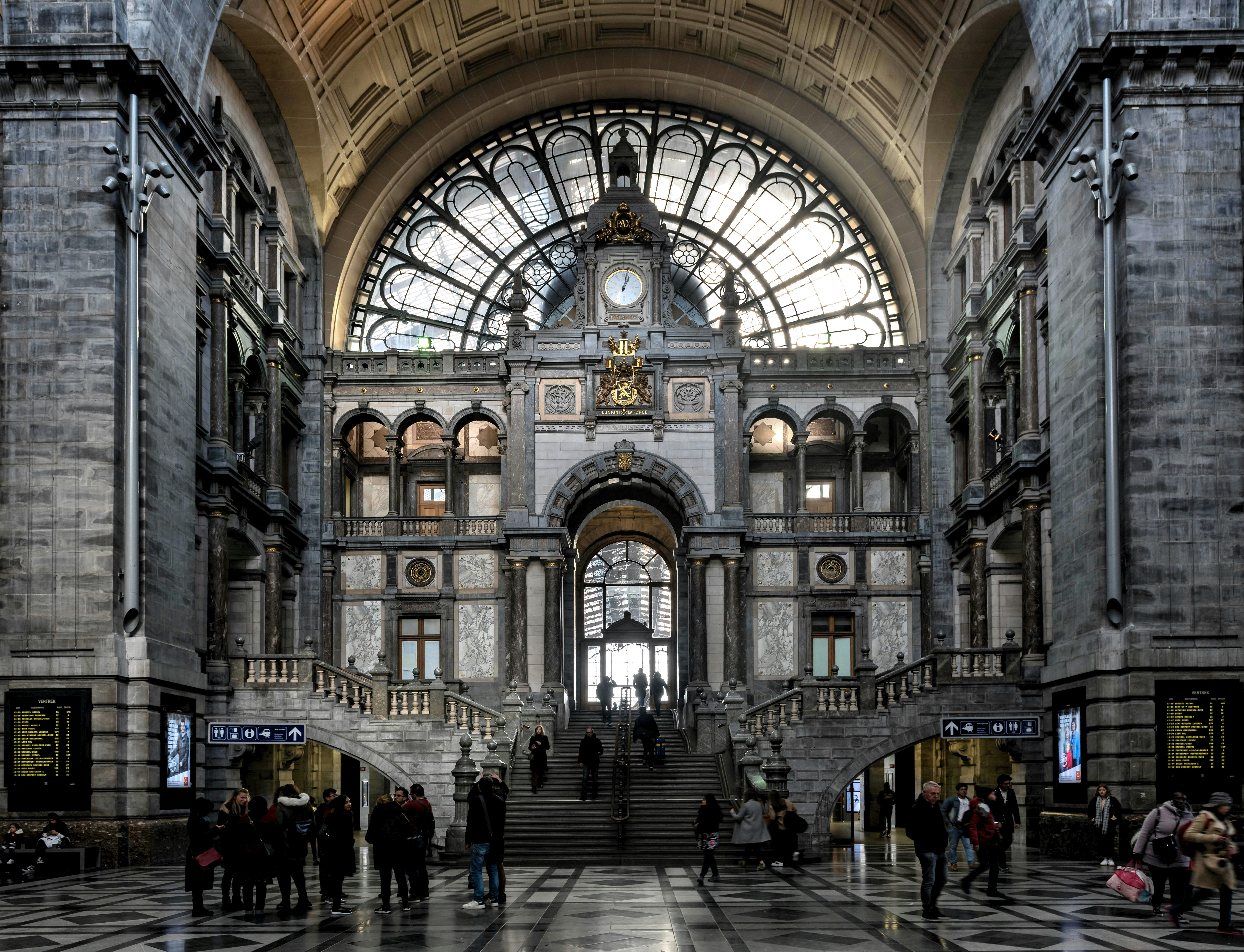 La Antwerpen-Centraal, conocida como la “Catedral de las Estaciones”, es una de las terminales ferroviarias más impresionantes de Europa. Construida entre 1895 y 1905 bajo el diseño de Louis De la Censerie, combina una estética palaciega con una monumental cúpula de piedra, interiores de mármol y una gran estructura de hierro y vidrio que cubre las vías.