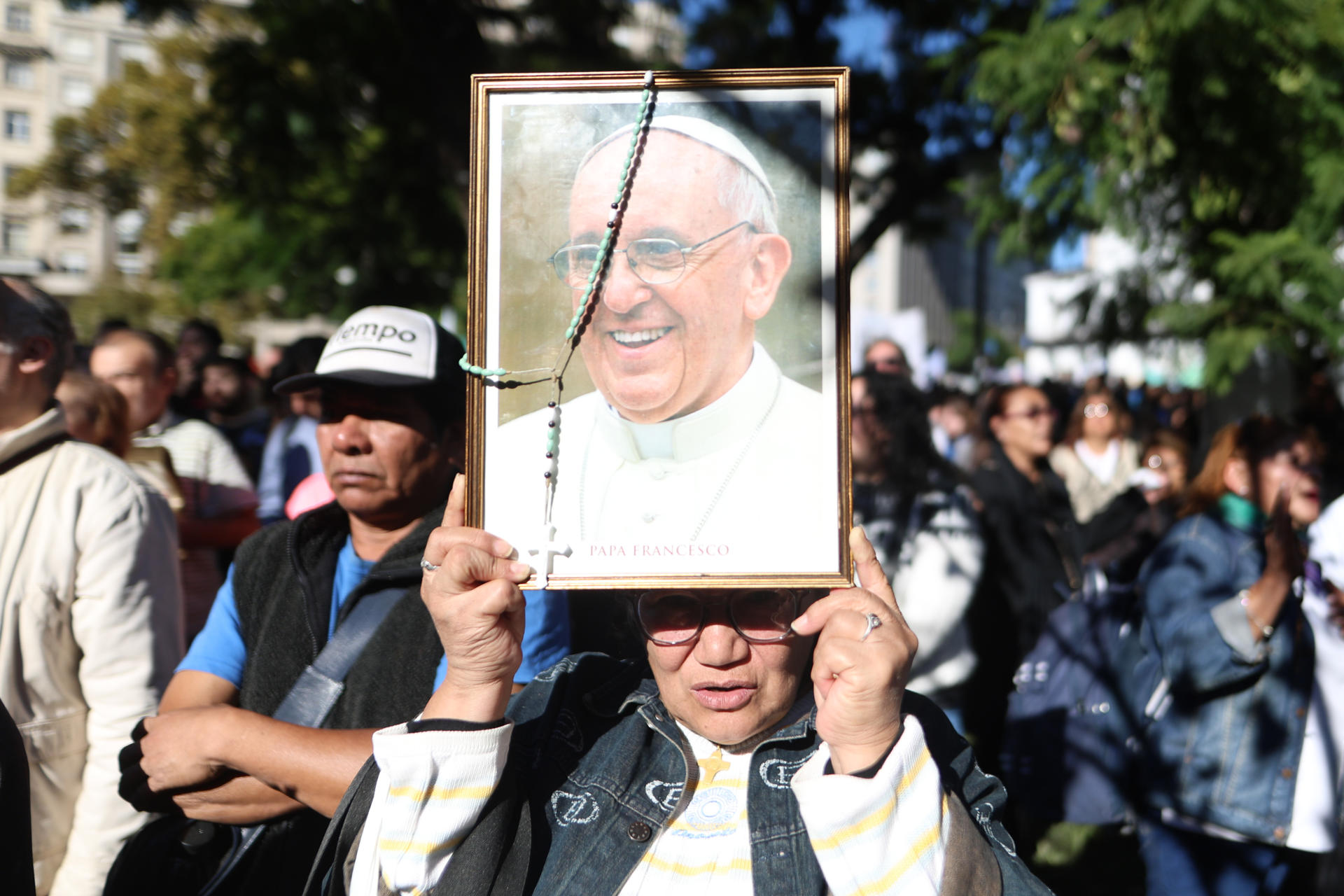 AME2631. BUENOS AIRES (ARGENTINA), 26/04/2025.- Una mujer sostiene un retrato del papa Francisco durante una caravana en su honor este sábado, al rededor de la Plaza de Mayo en Buenos Aires (Argentina). "Lloramos porque se murió el padre de todos, lloramos porque no terminamos de dimensionar y comprender su liderazgo internacional", dijo este sábado el arzobispo de Buenos Aires, Jorge García Cuerva, en la emotiva misa exequial por el papa Francisco celebrada en la catedral de la capital argentina. EFE/ Juan Ignacio Roncoroni