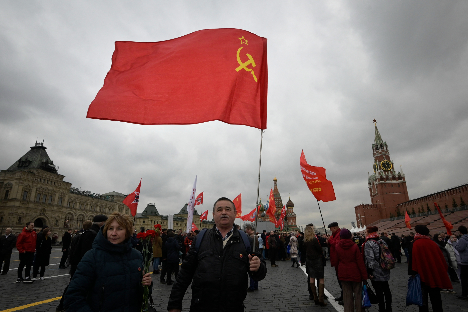 Un hombre sostiene la bandera del comunismo. Muchos  simpatizantes del Partido Comunista Ruso llevaban banderas rojas mientras se dirigían hacia el mausoleo del fundador de la Unión Soviética, Vladímir Ilyich Ulyanov, también conocido como Lenin, para conmemorar 152 años de su nacimiento.