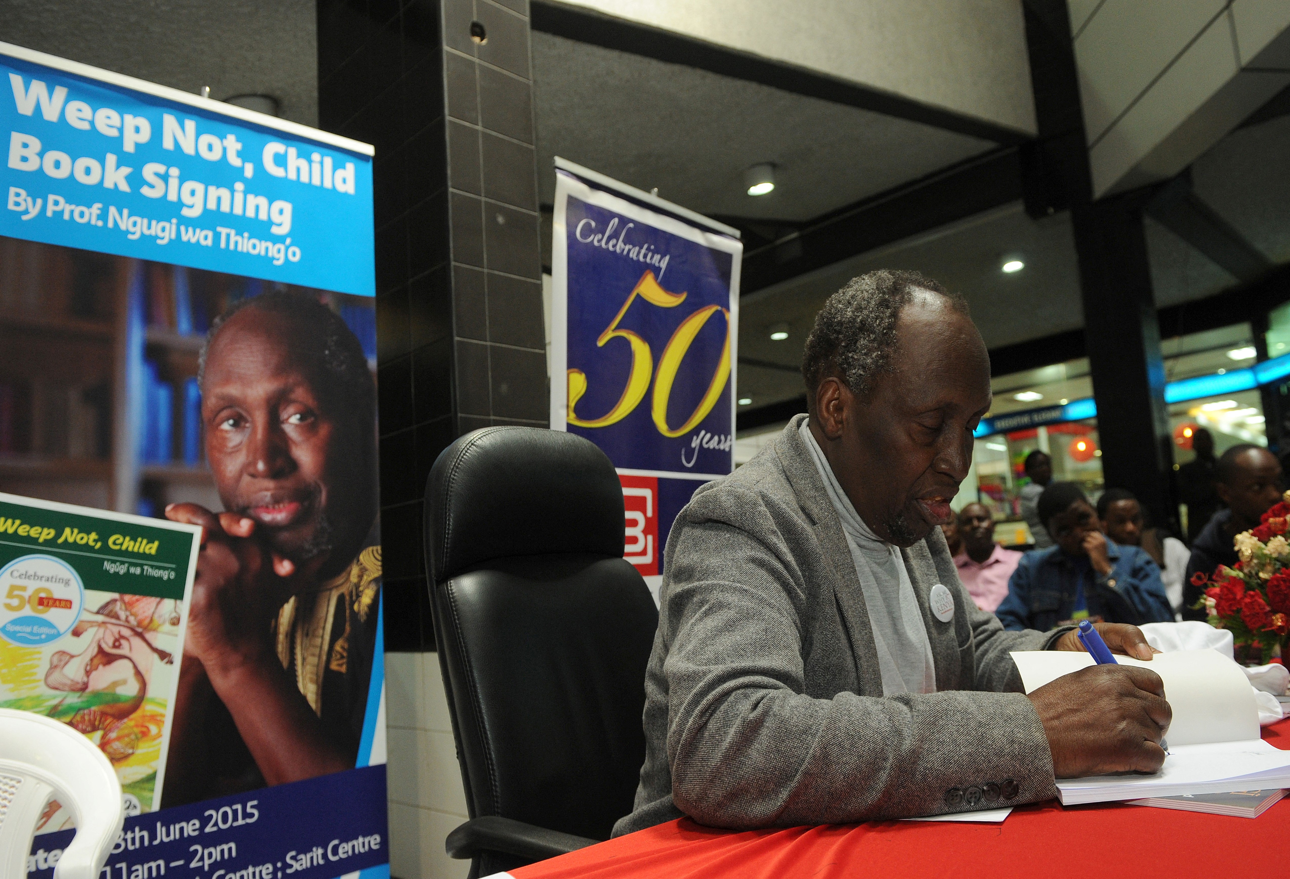 (FILES) Internationally celebrated author, playwright and critic, Kenyan Ngugi wa Thiong'o autographs a copy of one of his books for a fan, on June 13, 2015 during a book signing to celebrate the golden jubilee of his first book 'Weep Not Child' in the Kenyan capital, Nairobi.