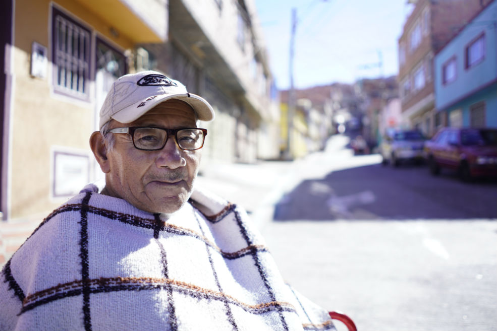 Antonio Gacha Romero, paciente con ELA frente a su casa en el Barrio Lucero Bajo. Gacha fue diagnosticado con túnel del carpo, Parkinson y Guillain-Barré. En mayo recibió el diagnóstico definitivo de Esclerosis Lateral Amiotrófica (ELA).Diego CuevasÉl no entiende bien qué le sucede, pero no puede caminar ni mover las manos. Su sobrina le consiguió una silla de ruedas por Facebook, pero don Antonio se pasa todo el día en la cama de un cuarto que arrienda con su esposa. Ella no lo puede alzar ni mover, por lo que don Antonio ya tiene una enorme escara en su espalda, una lesión que apareció por estar acostado durante largas horas. Pueden pasar uno o dos días para que le cambien los pañales y, como su silla de ruedas no logra entrar al baño, lo deben bañar en la entrada del cuarto cada ocho días.