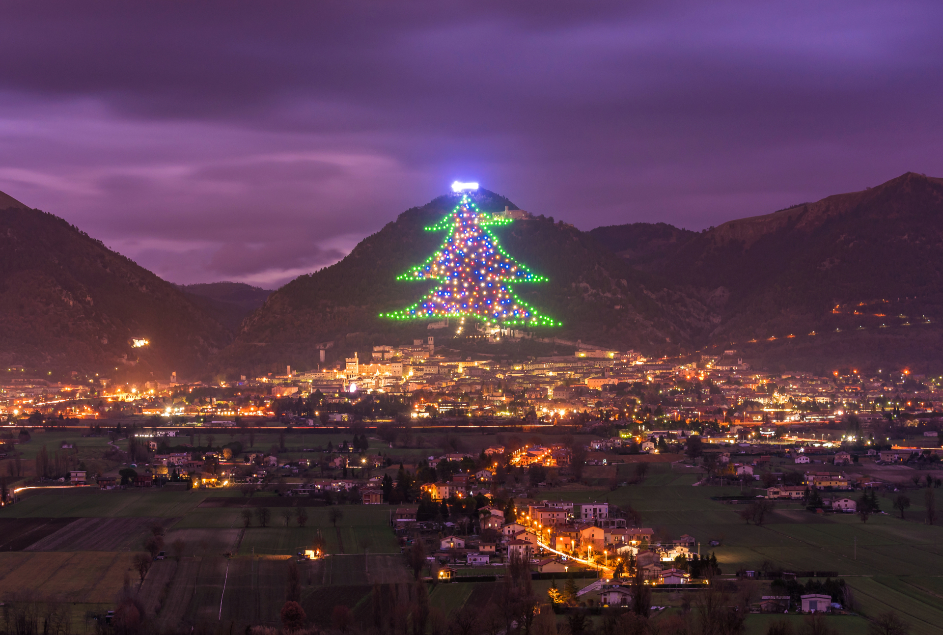 En la ciudad medieval de Gubbio, en el norte de Italia, se encuentra el árbol de Navidad más grande del mundo (récord Guinness desde 1991) en las laderas del monte Ingino. Lo curioso es que no es un árbol real, es más bien una forma conseguida a base de luces. Esta figura se extiende a lo largo de 650 metros por la pendiente del monte, está compuesto por casi un millar de luces multicolores y más de 10 kilómetros de cableado. Solo la estrella fugaz que brilla en la parte superior, lleva ya más de 250 luces.