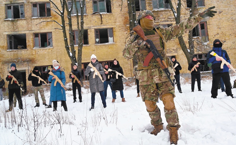 Un instructor militar enseña a civiles que sostienen réplicas de madera de rifles Kalashnikov, durante una sesión de entrenamiento en una fábrica abandonada en la capital ucraniana de Kiev el 30 de enero de 2022.