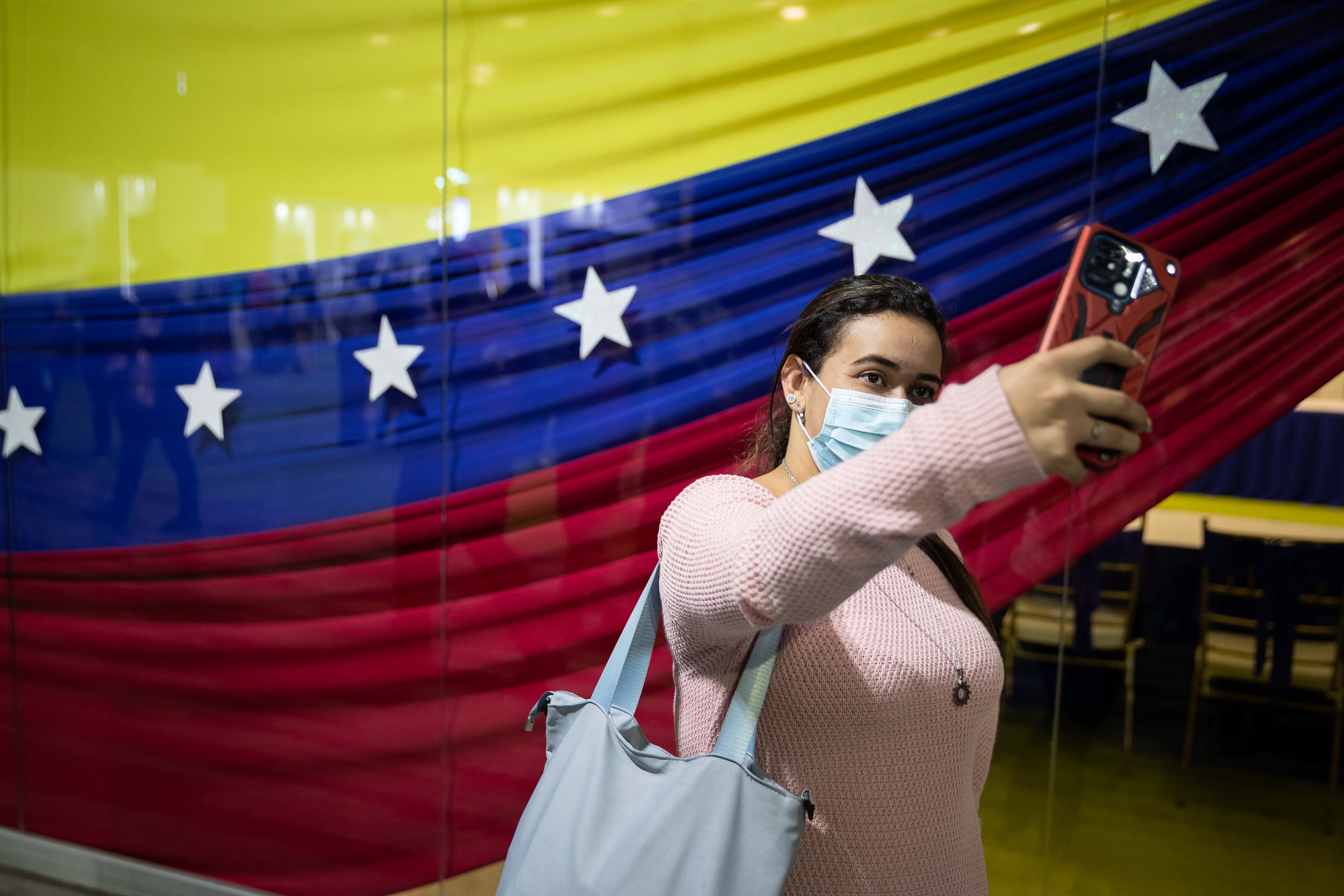 -FOTODELDÍA- AME7674. CARACAS (VENEZUELA), 16/09/2022.- Una mujer se fotografía con la bandera de Venezuela durante la "Expoferia Científico Tecnológica Industrial" de Irán y Venezuela hoy, en el Poliedro de Caracas (Venezuela). EFE/ Rayner Peña R.