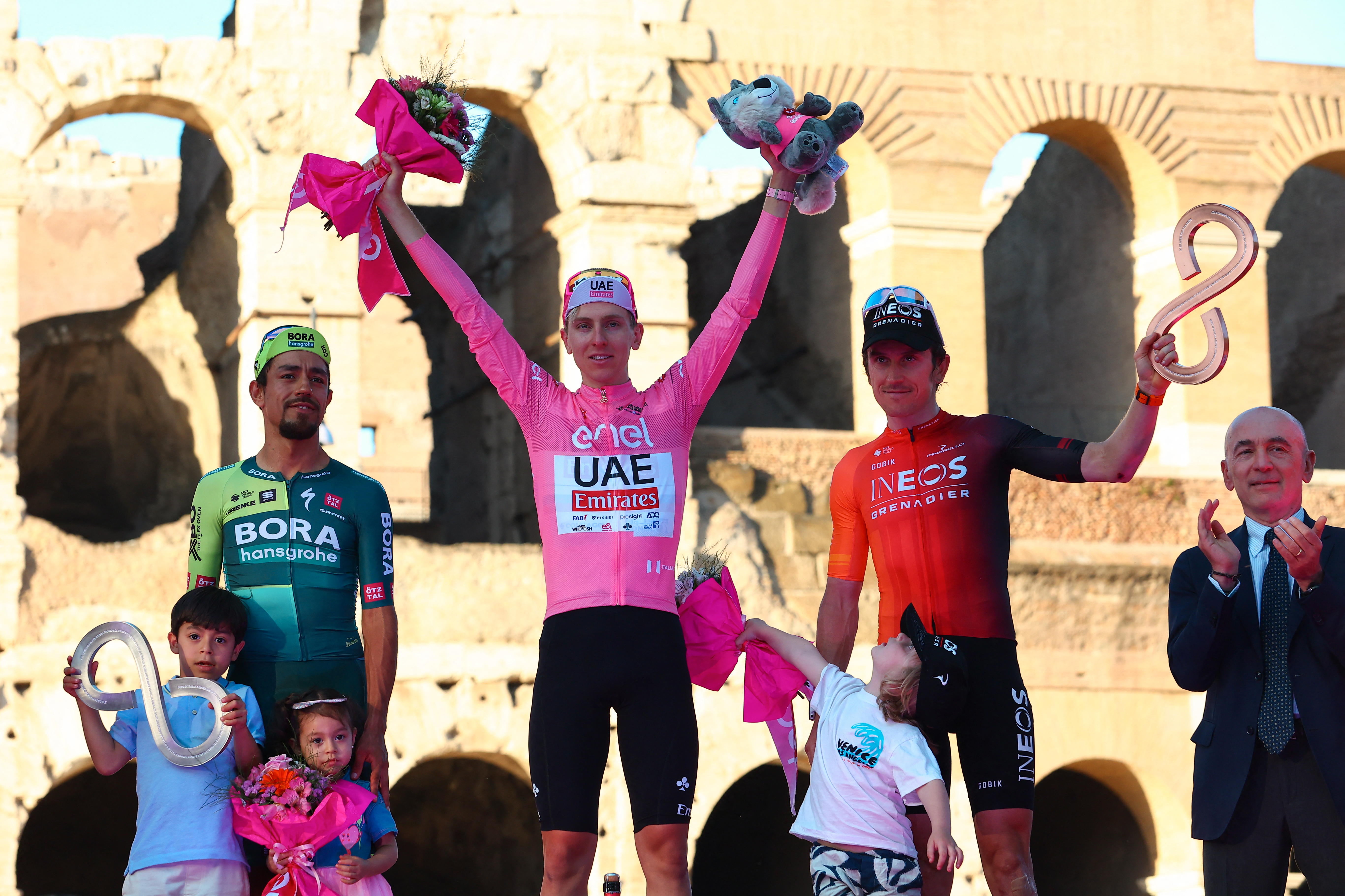 Team UAE's Slovenian rider Tadej Pogacar celebrates his overall leader's pink jersey on the podium in front of the Colosseum, flanked by overall second-placed Team Bora's Colombian rider Daniel Martinez (L) and overall third-placed Team Ineos' British rider Geraint Thomas (R) after the 21st and last stage of the 107th Giro d'Italia cycling race, 125km from Rome to Rome on May 26, 2024.
 (Photo by Luca Bettini / AFP)