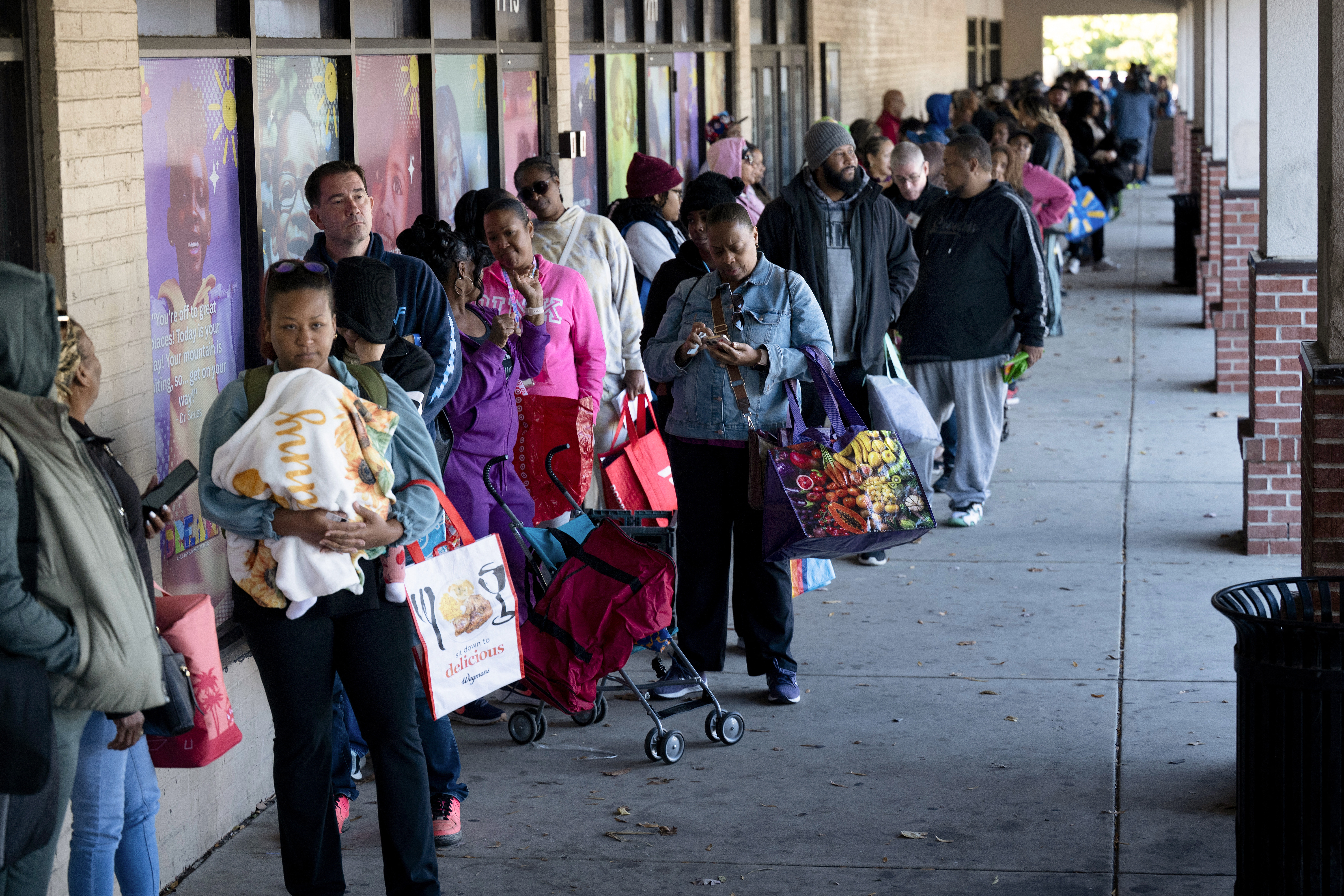 People line up to receive food for furloughed federal workers at No Limits Outreach Ministries oln October 21, 2025 in Hyattsville, Maryland. The US government shutdown dragged into a third week, with Congress gridlocked in a clash over spending and no resolution in sight to a crisis that has already cost thousands of jobs. (Photo by Brendan Smialowski / AFP)