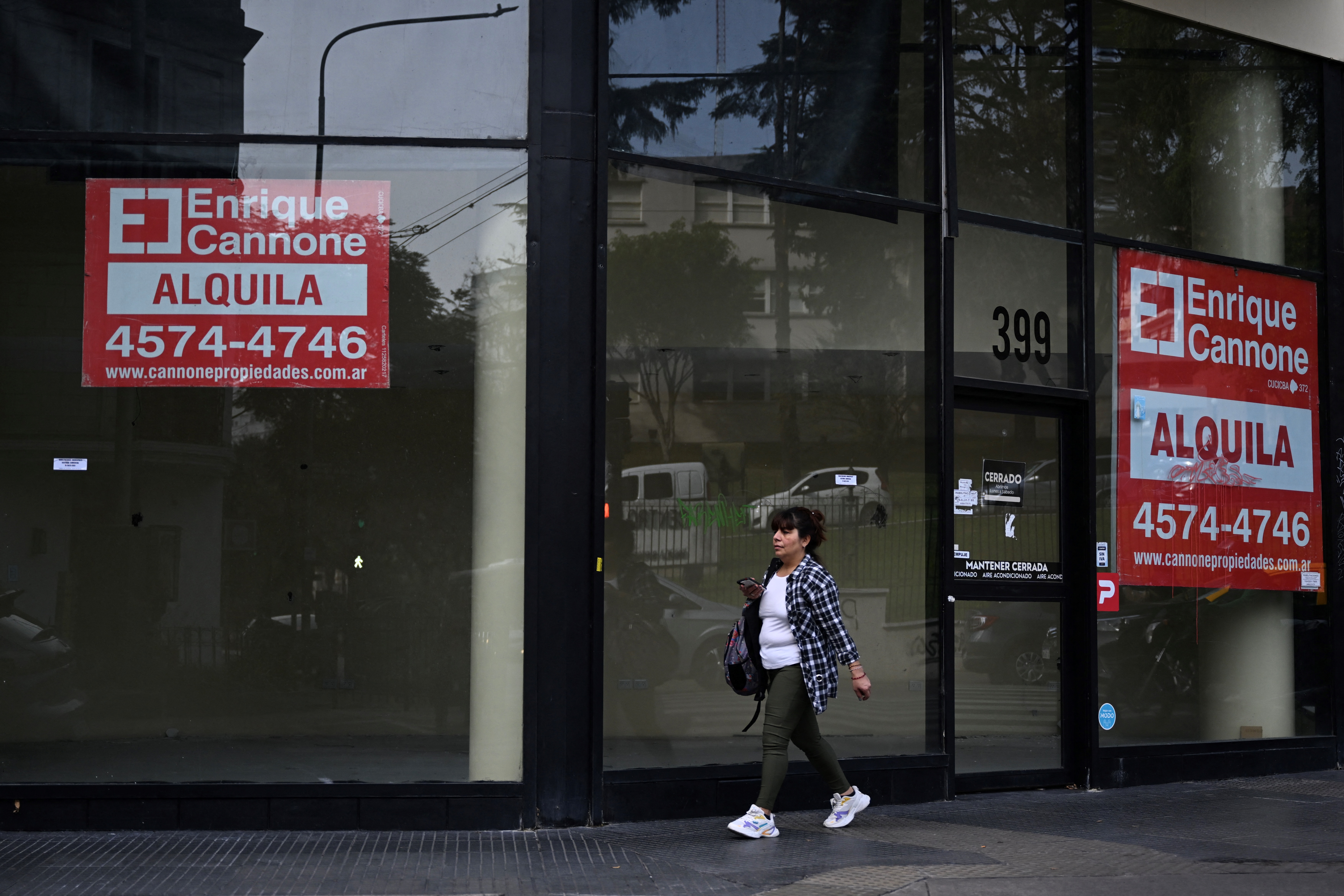 A woman walks next to a commercial establishment with rent price signs on a street in Buenos Aires on June 13, 2024.