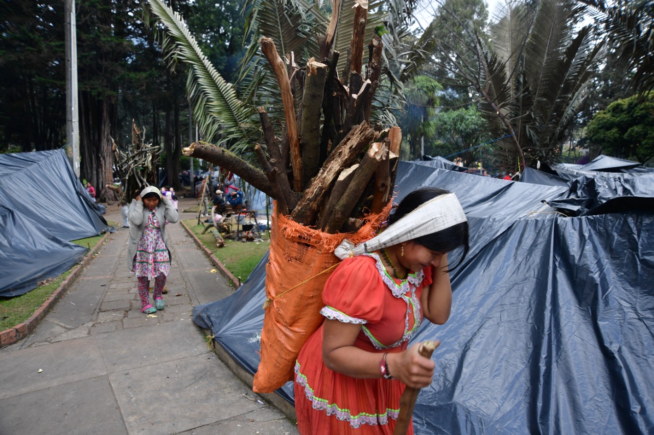 Dos mujeres cargan leña. El helado clima de Bogotá entra por todas partes, y es necesario alimentarse y calentarse.