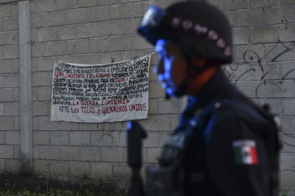 Policía de Iguala junto a un cartel amenazante de la organización criminal Guerreros Unidos.