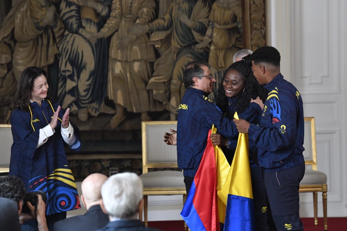 El presidente de Colombia, Gustavo Petro, le entrega el pabellón nacional a Flor Denis Ruiz y Kevin Quintero.