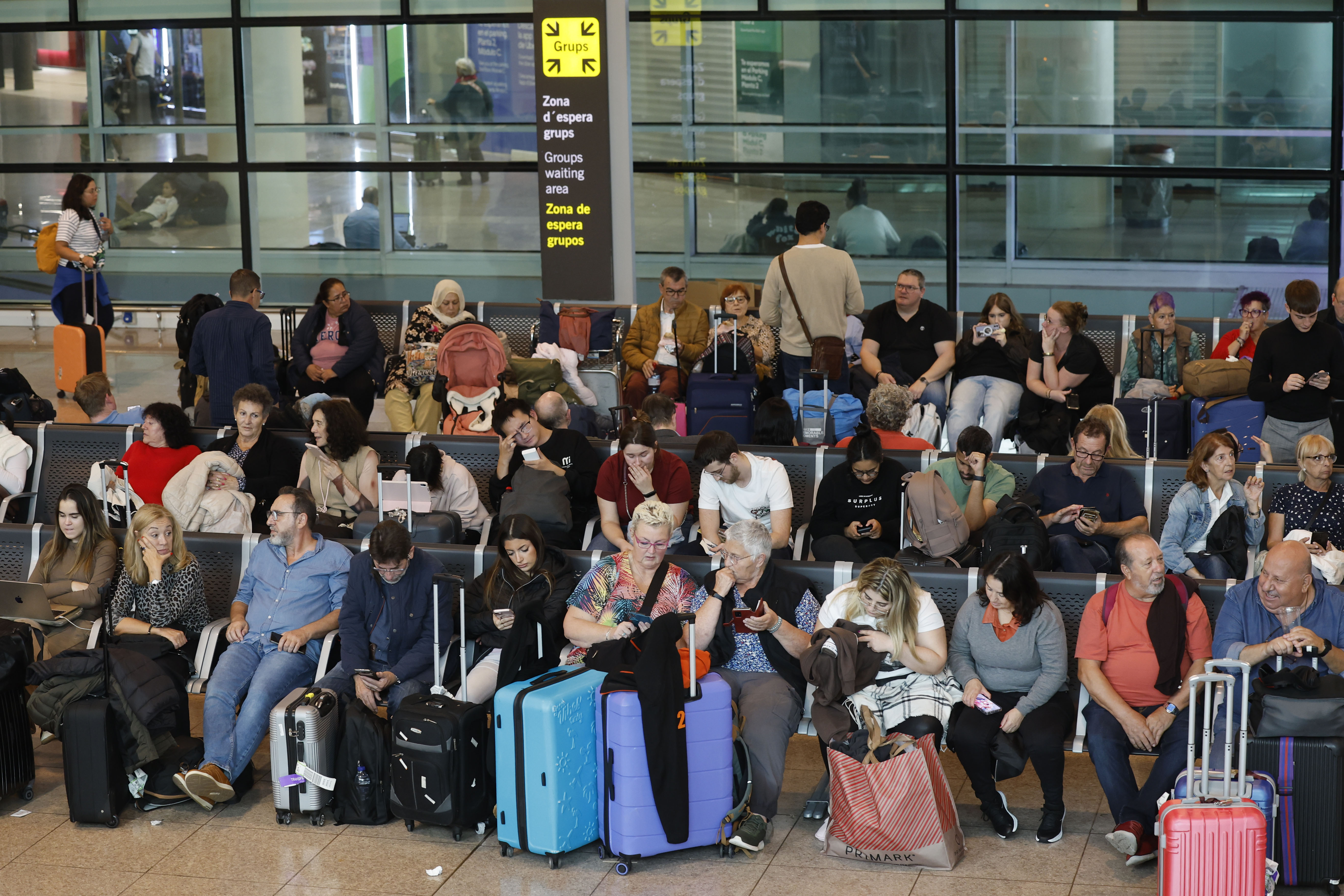 GRAFCAT094. BARCELONA, 04/11/2024.- Decenas de pasajeros esperan en la zona intermodal del Aeropuerto de El Prat para recabar información sobre sus vuelos después de que las fuertes tormentas hayan obligado a cancelar hasta ahora medio centenar de vuelos de salida y a desviar otros 17 en el Aeropuerto de Barcelona-El Prat, donde se han producido además algunas inundaciones en los vestíbulos de la T-1 y en el aparcamiento. EFE/Toni Albir
