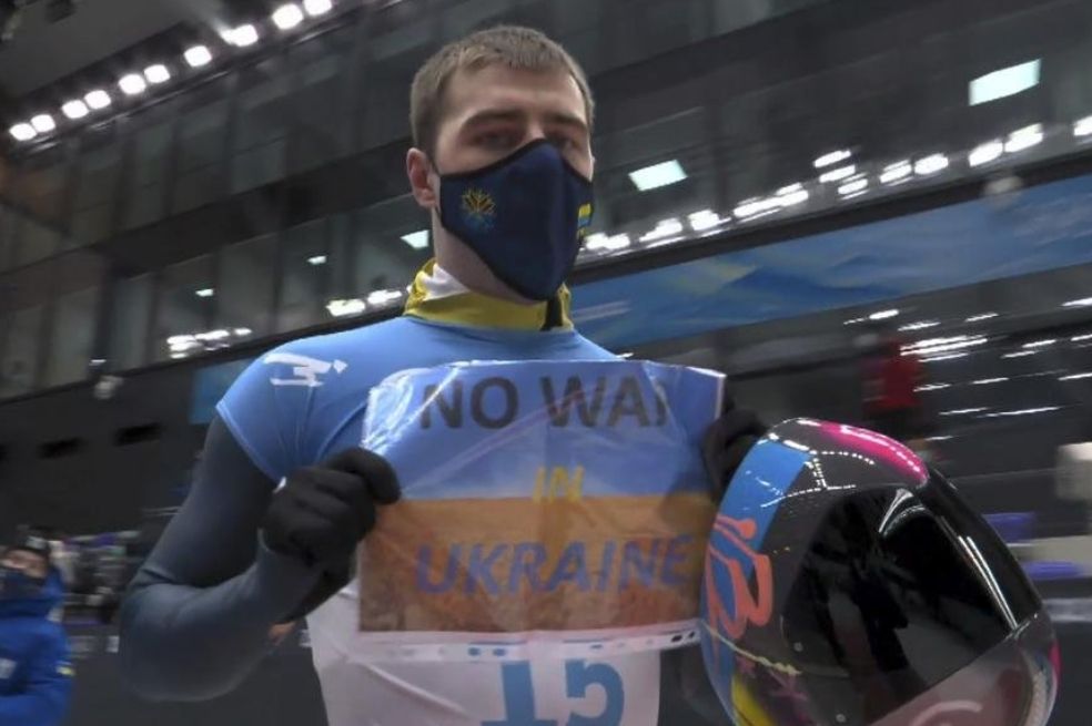 Vladyslav Heraskevych sostiene un cartel ante la cámara en la que pide que se acabe la guerra en Ucrania.