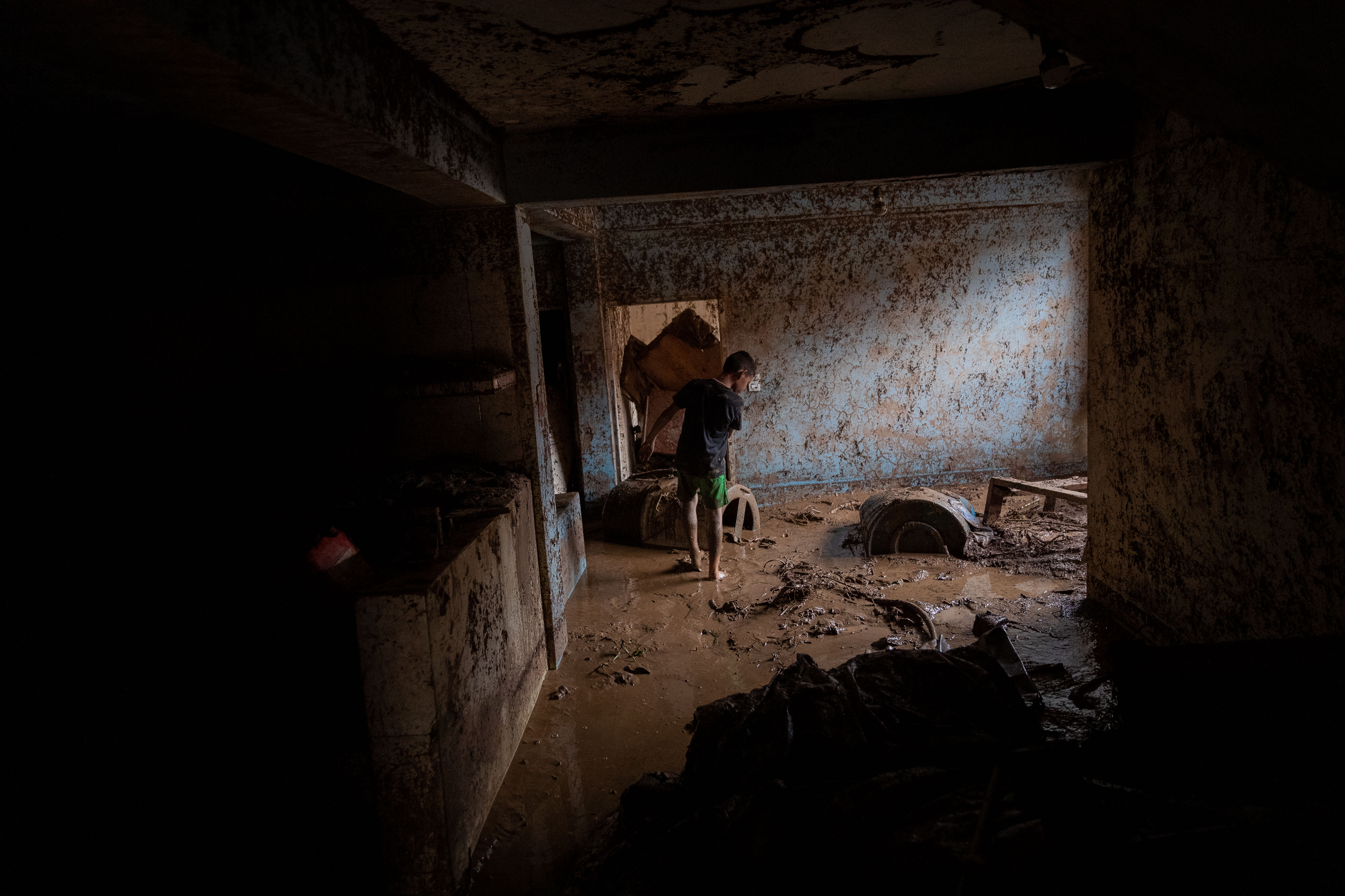 AME3286. TEJERIAS (VENEZUELA), 09/10/2022.- Un niño camina entre el lodo que quedó en su vivienda tras las lluvias y desbordamiento de la quebrada (rio) Los Patos en Las Tejerias, hoy en el estado Aragua (Venezuela). La crecida de una quebrada este sábado arrastró viviendas, mobiliario urbano, e inundó las calles de la localidad, arrasando con todo lo que el agua encontró a su paso. El Gobierno desplegó hoy organismos de salvamento, seguridad ciudadana, así como cuadrillas de mantenimiento y limpieza, y personal de diversas instituciones para "la atención integral del pueblo", dijo el presidente Nicolás Maduro a través de su cuenta de Twitter.EFE/ Rayner Peña R.