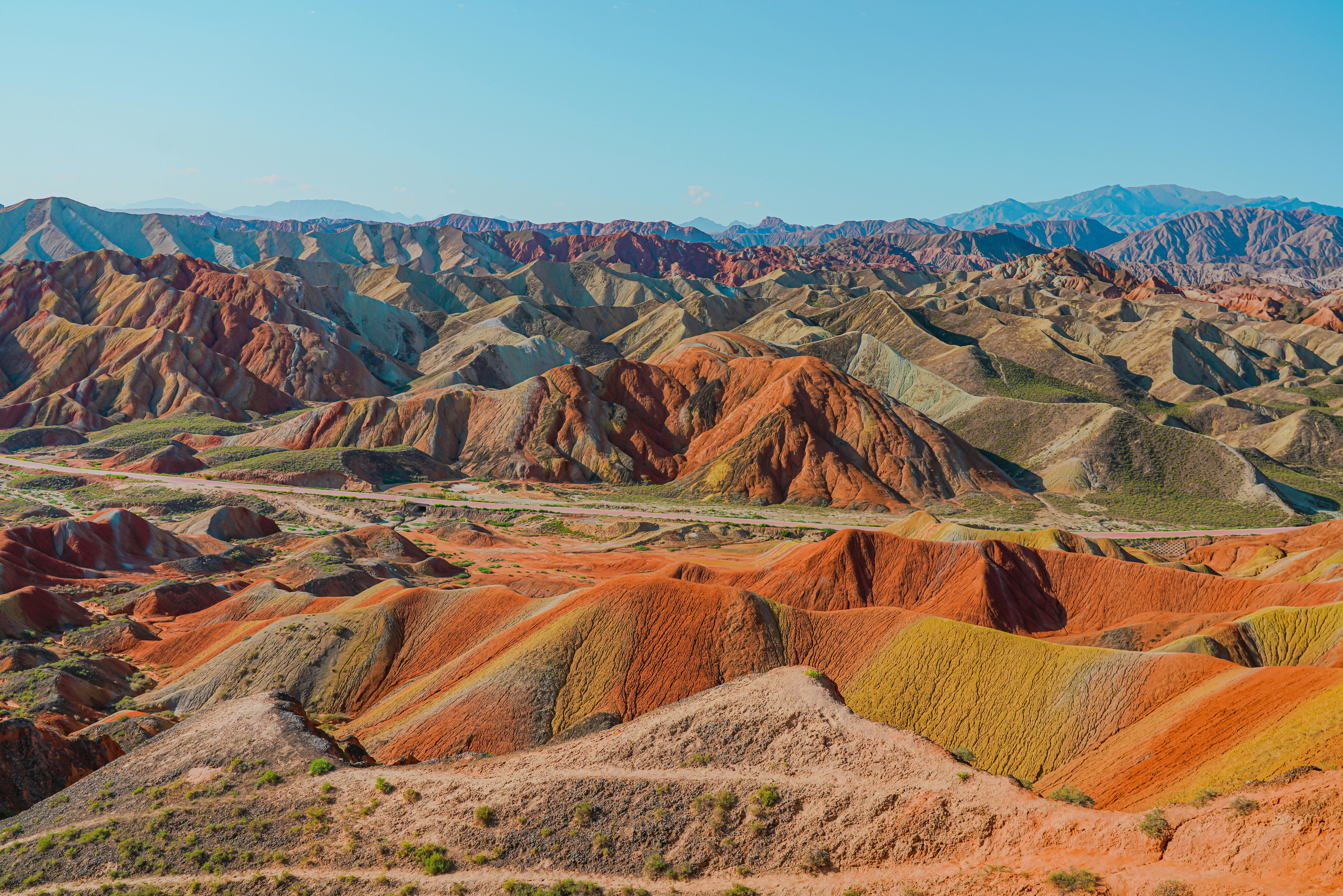 El Parque Geológico Nacional Zhangye Danxia es uno de los paisajes más impresionantes de China y destaca por sus enormes montañas de colores que parecen pintadas a mano. Ubicado en la provincia de Gansu, este parque formado durante millones de años combina capas rojizas, amarillas, verdes y violetas creadas por minerales y procesos geológicos, dando origen a las famosas “montañas arcoíris”. Los visitantes pueden recorrer miradores panorámicos en autobús, caminar por senderos ligeros y contemplar al amanecer o atardecer cómo los colores rojizos, amarillos y naranjas de las montañas se intensifican con la luz del sol.