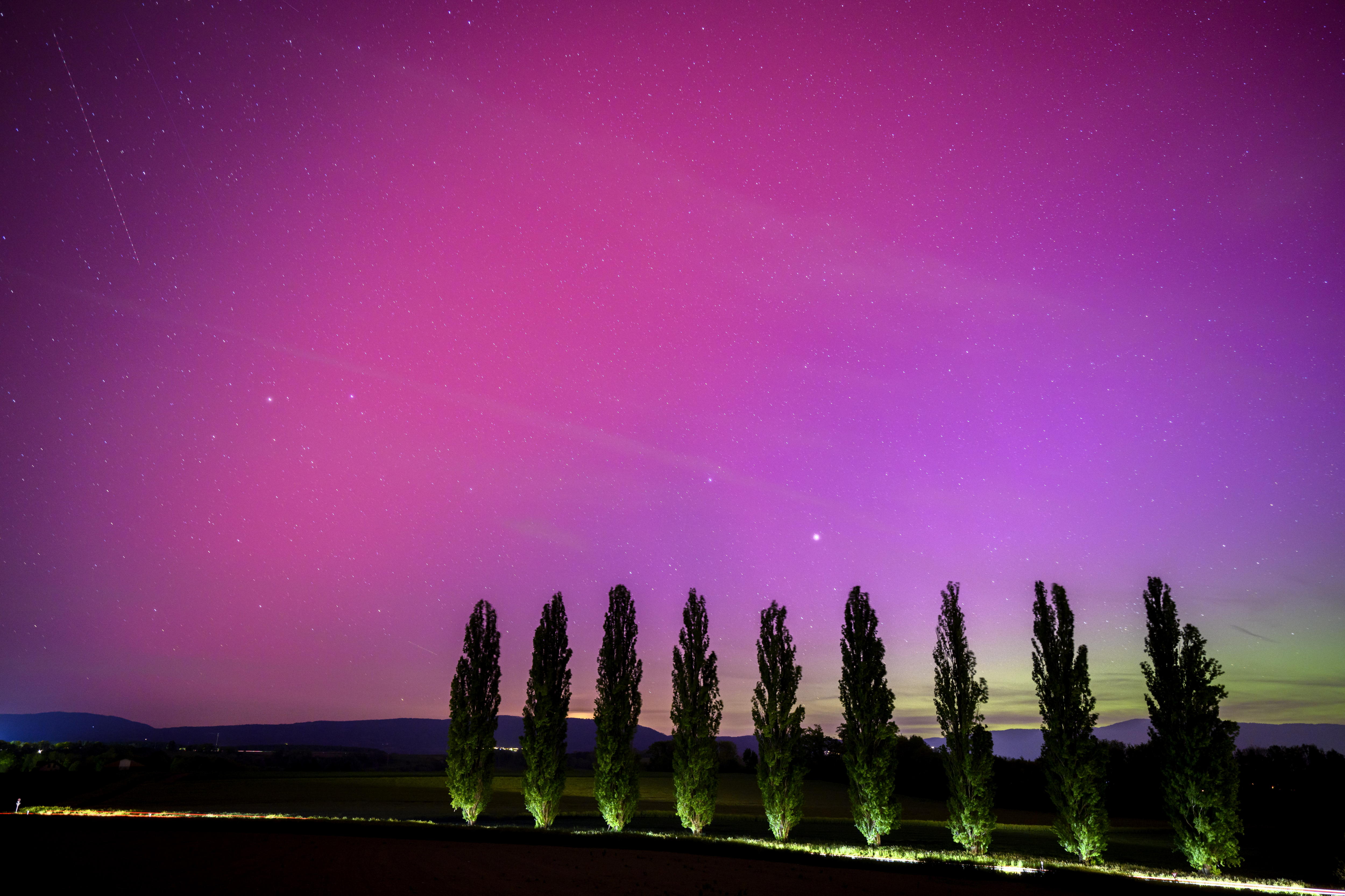 Daillens (Switzerland), 11/05/2024.- A car drives on the road and illuminates poplars under the Northern lights (aurora borealis) glow in the night sky above the village of Daillens, Switzerland, 11 May 2024. The National Oceanic and Atmospheric Administration (NOAA) of America has warned that the strongest geomagnetic storm for 20 years is set to hit Earth, making the Aurora Borealis, or Northern Lights, visible at much lower geomagnetic latitudes than usual. (tormenta, Suiza) EFE/EPA/LAURENT GILLIERON
