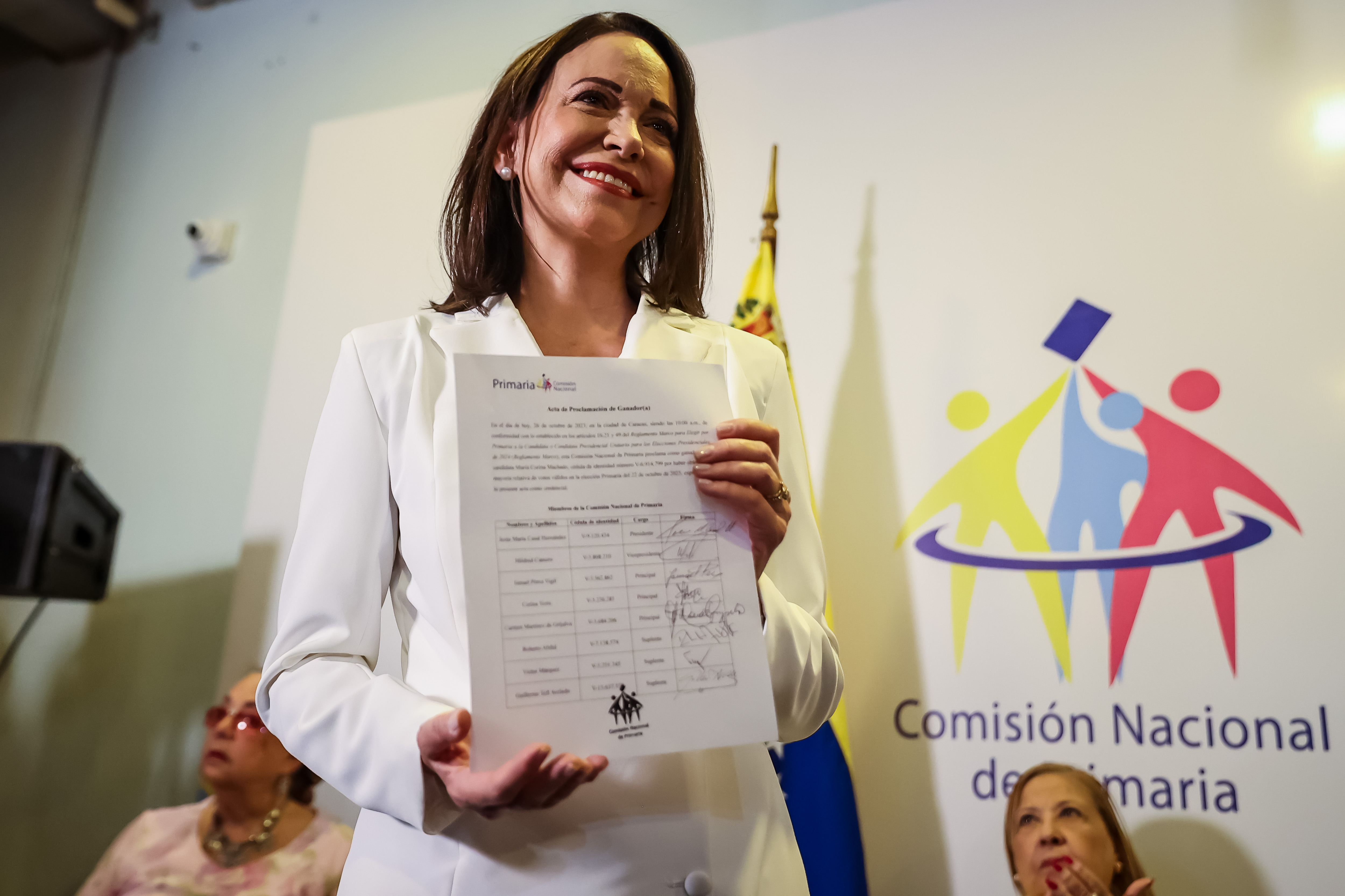 AME837. CARACAS (VENEZUELA), 26/10/2023.- La candidata Maria Corina Machado recibe el documento, firmado por los Miembros de la Comisión Nacional de Primarias, que la proclama como ganadora de las elecciones internas de la oposición, hoy en Caracas (Venezuela). La exdiputada María Corina Machado, vencedora indiscutible de las elecciones primarias de Venezuela con 92 % de los votos, fue proclamada este jueves como la candidata de la oposición mayoritaria para las elecciones presidenciales de 2024, en las que buscará derrotar al chavismo, en el poder desde hace 24 años. EFE/ Miguel Gutiérrez