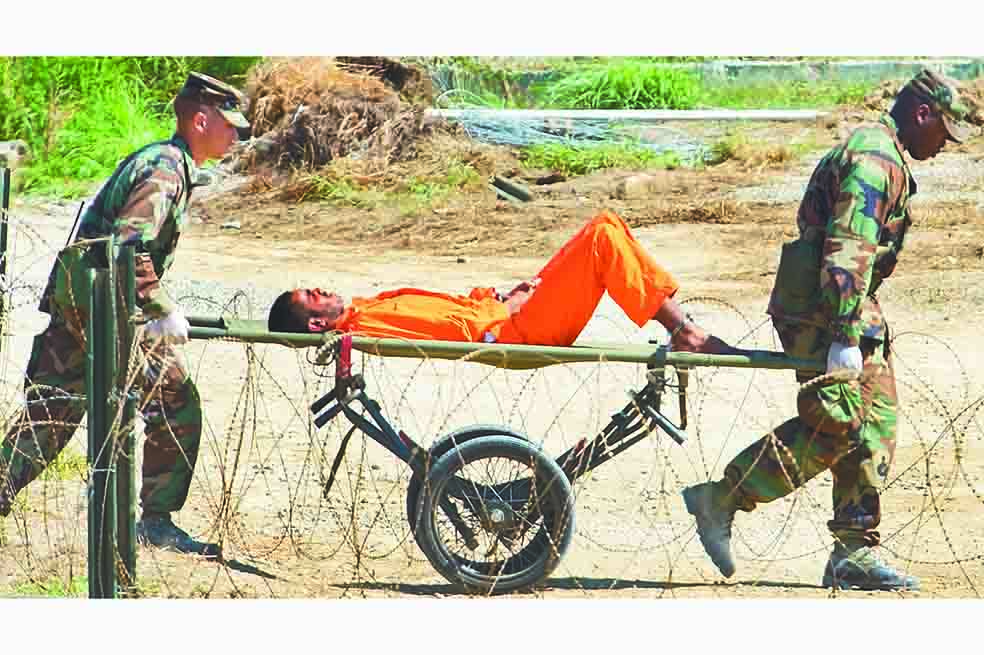 Soldados estadounidenses cargan a un preso de Guantánamo en una camilla. /AFP