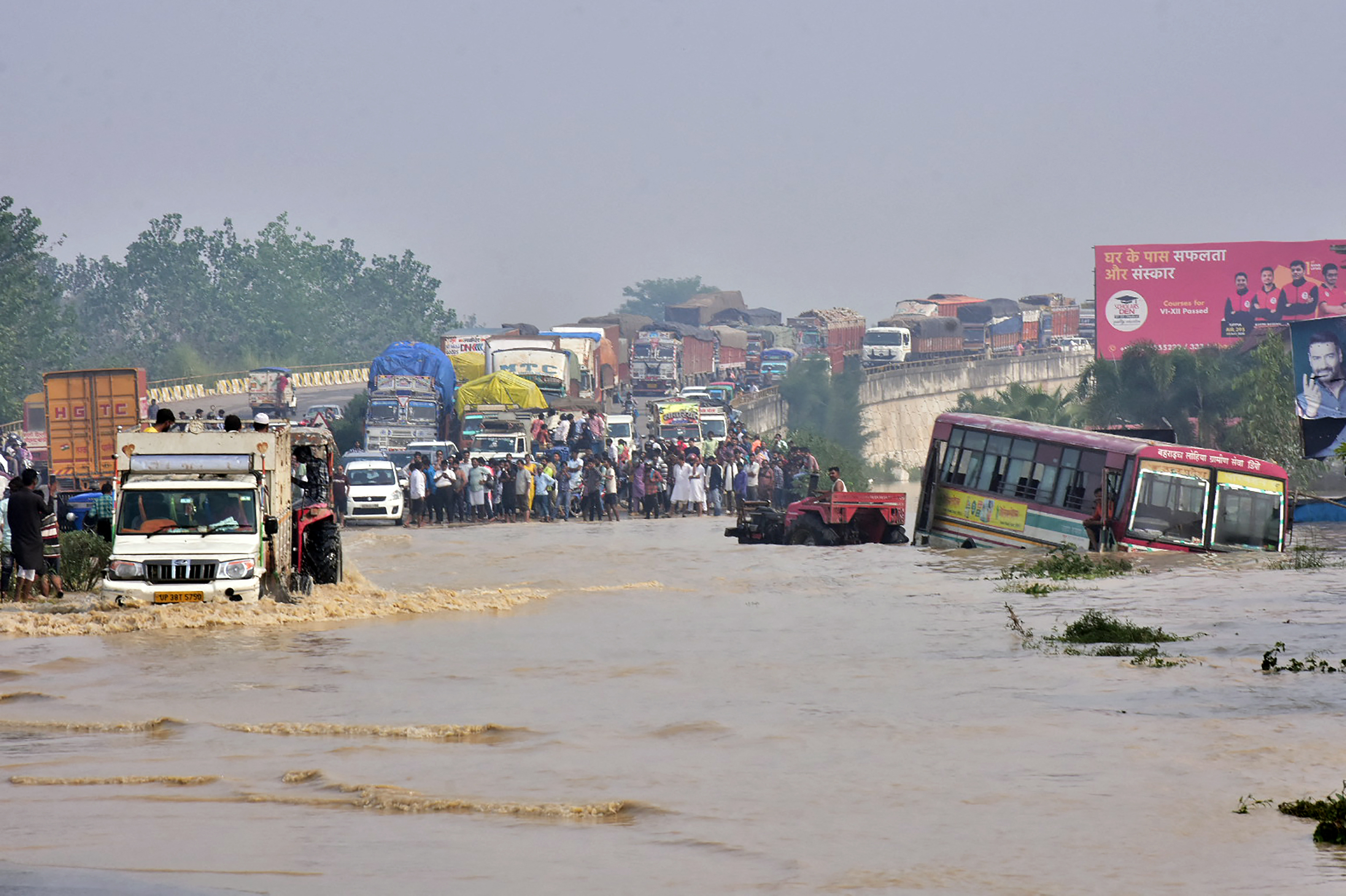 Commuters stand on a flyover on a flooded national highway after river Kosi overflowed following heavy rains near Rampur in India's Uttar Pradesh state on October 20, 2021, as the death toll from days of flooding and landslides in India and Nepal crossed 100. (Photo by AFP)