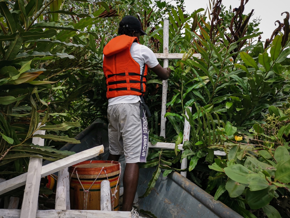 un hombre clava una cruz en una zona con mucha vegetación
