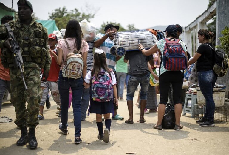 Una mujer venezolana camina con su hija hacia su casa en Ureña luego de que terminaran las clases en su colegio en Cúcuta. / AFP
