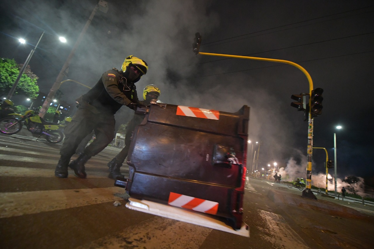 Un policía corre un contenedor de basura en la vía