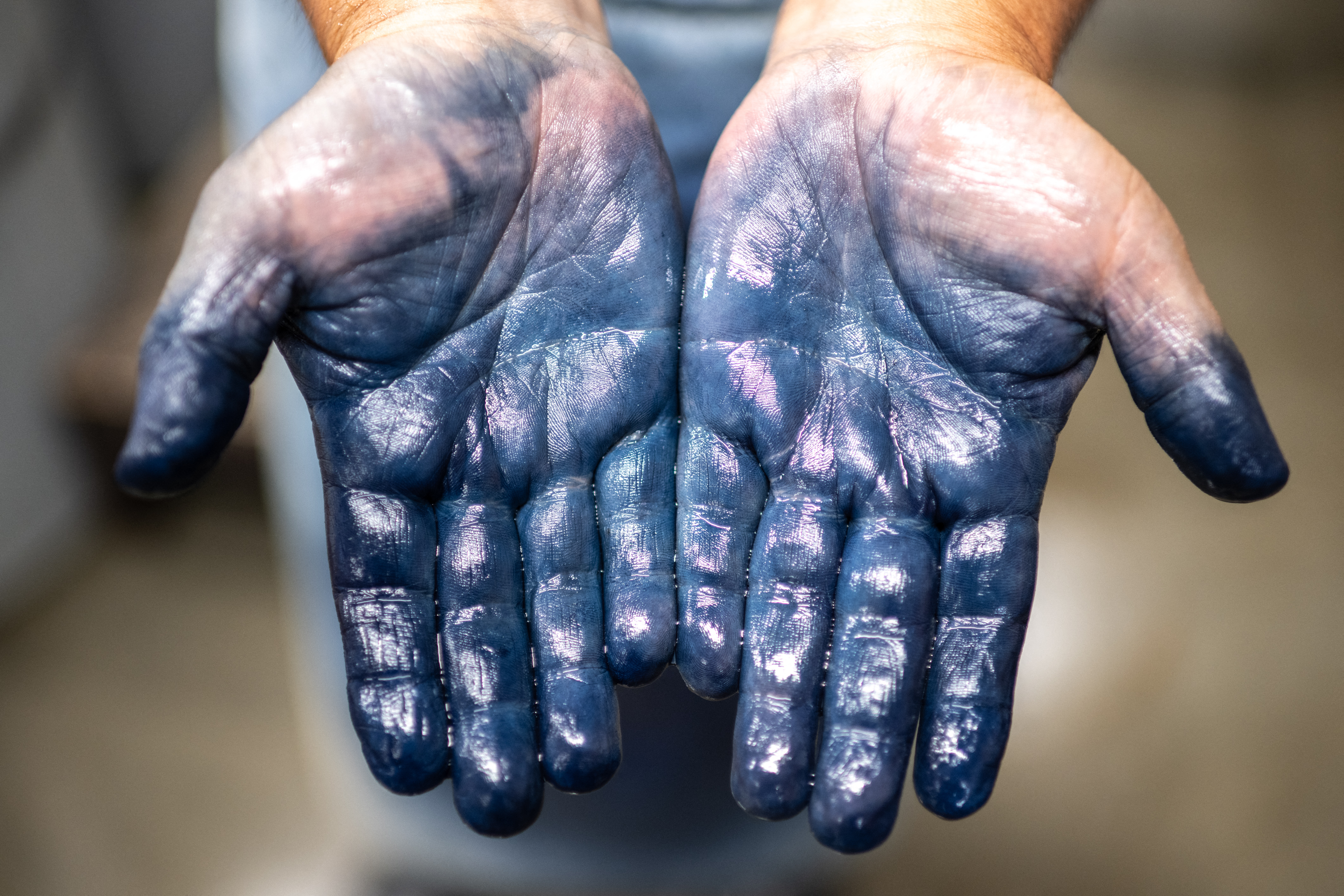 TOPSHOT - This picture taken on September 4, 2024 shows the hands of dyeing craftsman Yoshiharu Okamoto at the Momotaro Jeans factory in the Kojima district of Okayama.