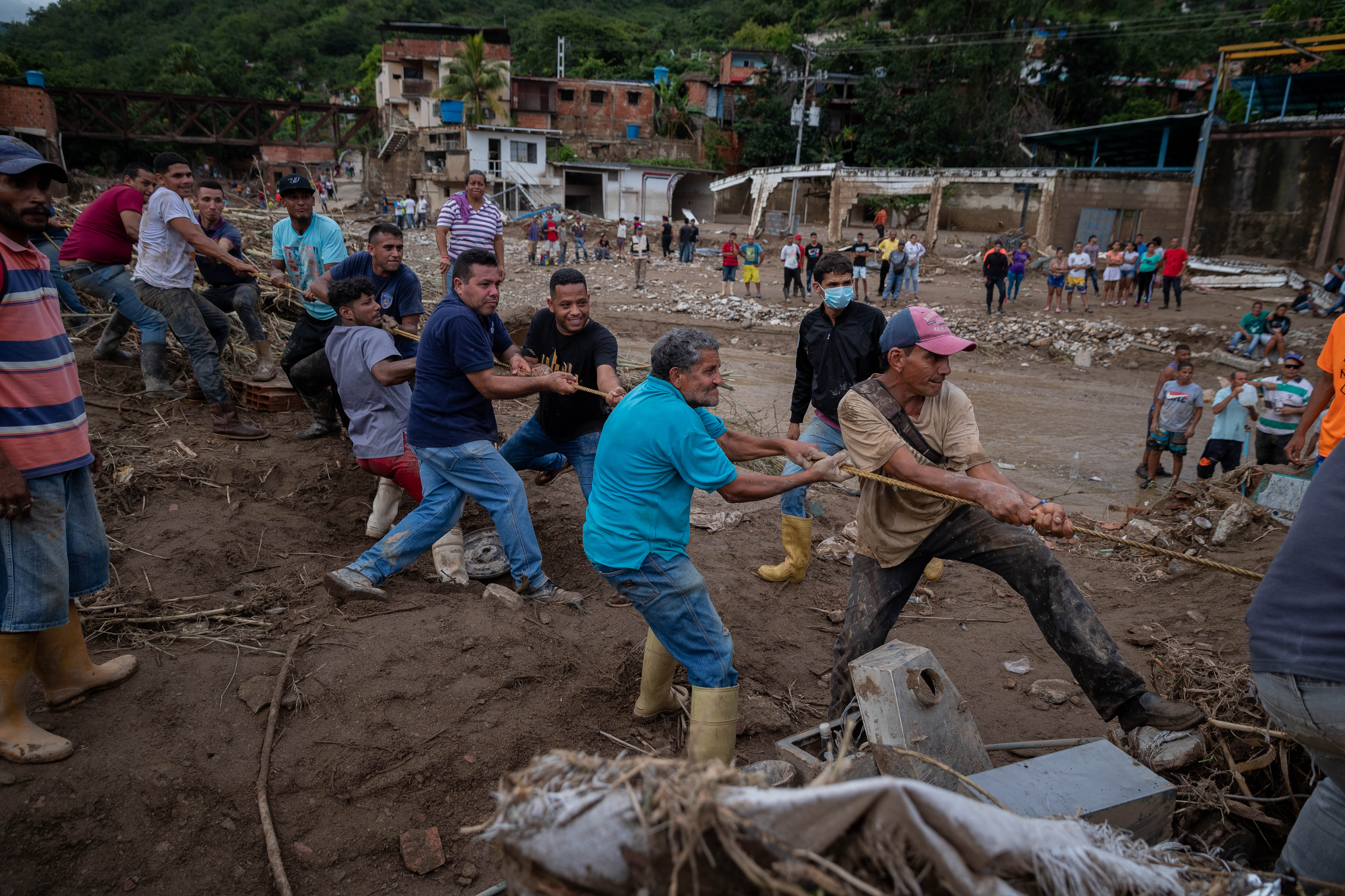 ACOMPAÑA CRÓNICA: VENEZUELA LLUVIAS***AME3304. LAS TEJERÍAS (VENEZUELA), 09/10/2022.- Habitantes colaboran hoy para retirar los destrozos tras el desbordamiento de la quebrada Los Patos, en Las Tejerías, estado Aragua (Venezuela). Algunos habitantes de Las Tejerías, en la zona central de Venezuela, recuerdan este domingo los gritos de la tragedia, mientras otros son incapaces de describir la noche del sábado, cuando esta pequeña ciudad fue arrasada por una quebrada desbordada, que se llevó a más de un centenar de personas, de las que, al menos, 25 murieron y más de 50 siguen desaparecidas. EFE/ Rayner Peña R