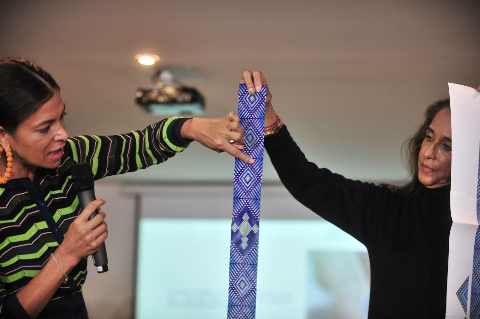 Mercedes Salazar y Pilar Castaño presentan el tejido en chaquiras confeccionado por indígenas del Putumayo que simboliza “el ojo de Dios que orienta y el camino de la vida”. El color azul representa a la Virgen María. Fotografía: Óscar Pérez