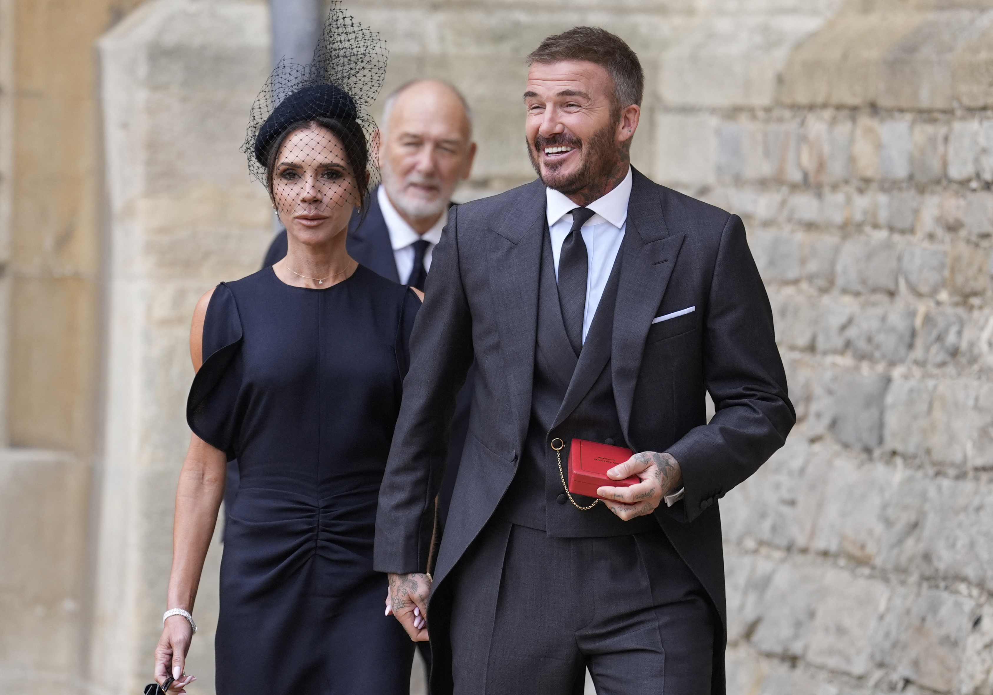 Former England footballer David Beckham (R) comes out into the yard followed by his wife singer and fashion designer Victoria Beckham (L) and his father Ted (C) to pose for the media with his medal after being appointed as a Knight Bachelor (Knighthood) for services to sport and charity at an investiture ceremony at Windsor Castle on November 4, 2025. (Photo by Andrew Matthews / POOL / AFP)