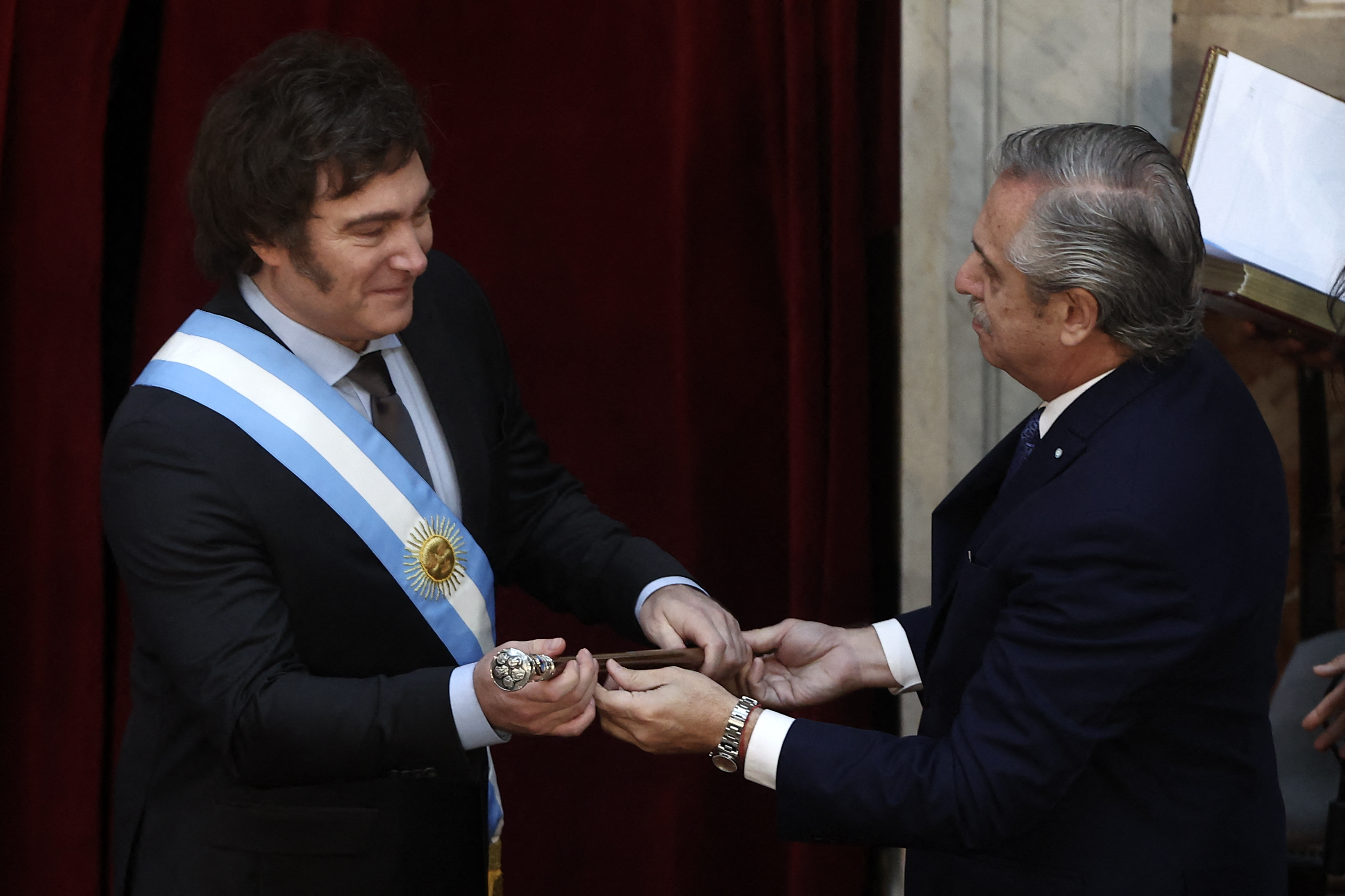 El presidente entrante de Argentina, Javier Milei (izq.), recibe el bastón presidencial del presidente saliente, Alberto Fernández, durante su ceremonia de toma de posesión en el Congreso.