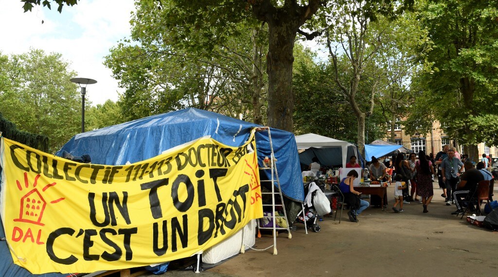 Los refugiados latinos se paran junto a una pancarta que dice "Una casa es un derecho" en la explanada del ayuntamiento de Saint-Ouen, cerca de París. / AFP