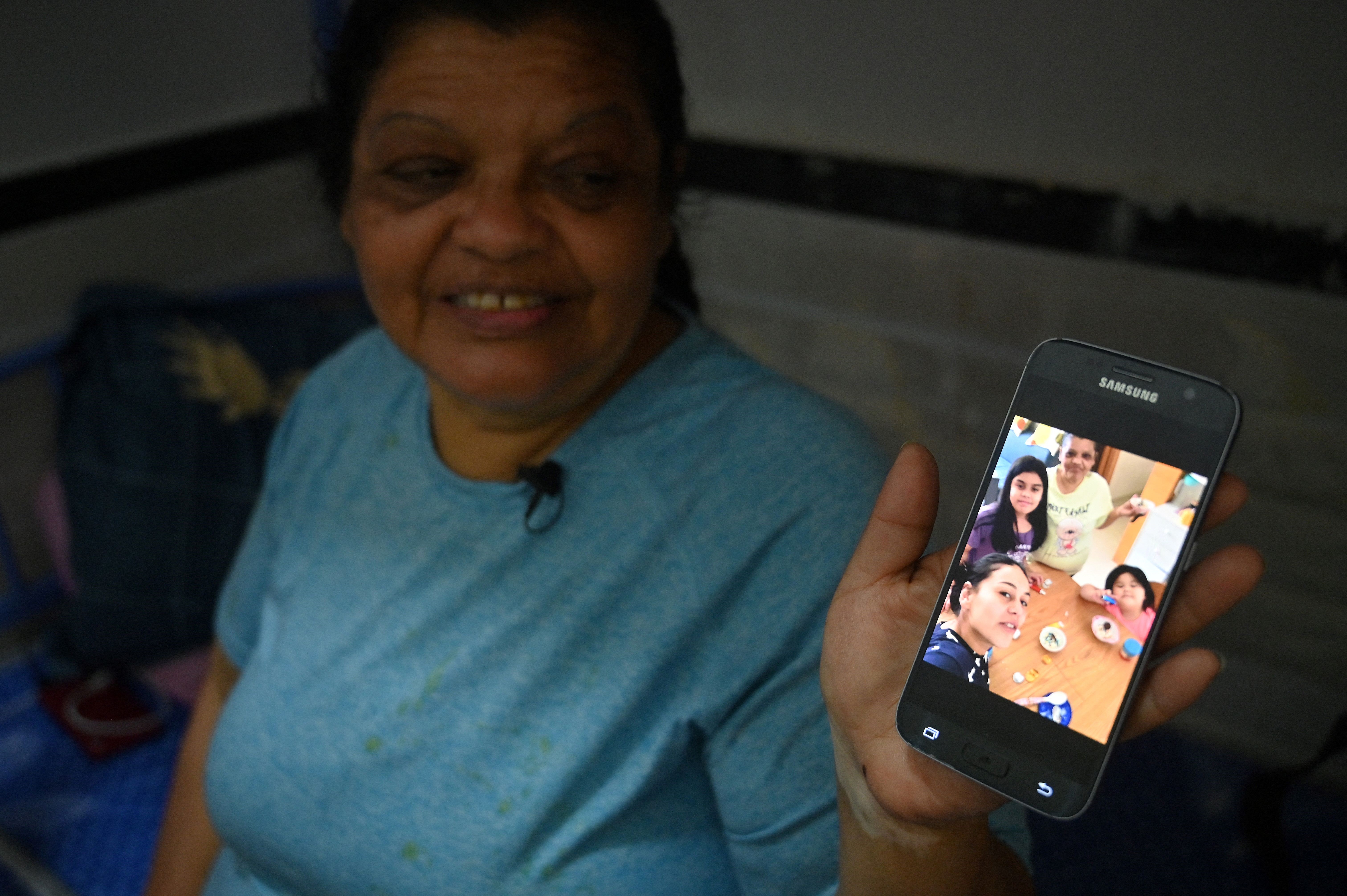 Esta foto tomada el 9 de mayo de 2022 muestra a la ciudadana peruana Zoila Lecarnaque Saavedra, recientemente liberada después de cumplir un tiempo en prisión por tráfico de drogas y ahora a la espera de ser deportada, mostrando fotos de su familia en su teléfono en un albergue abarrotado en Hong Kong.