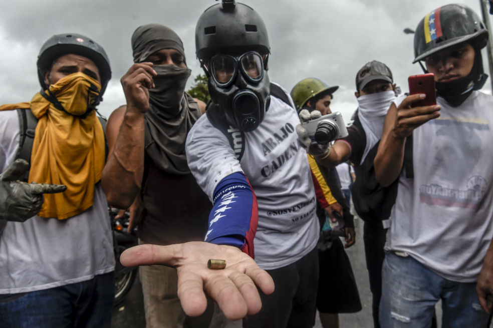 Activistas de la oposición muestran un casquillo de bala durante una manifestación contra el gobierno del presidente Nicolás Maduro a lo largo de la carretera de Francisco Fajardo en Caracas. /AFP