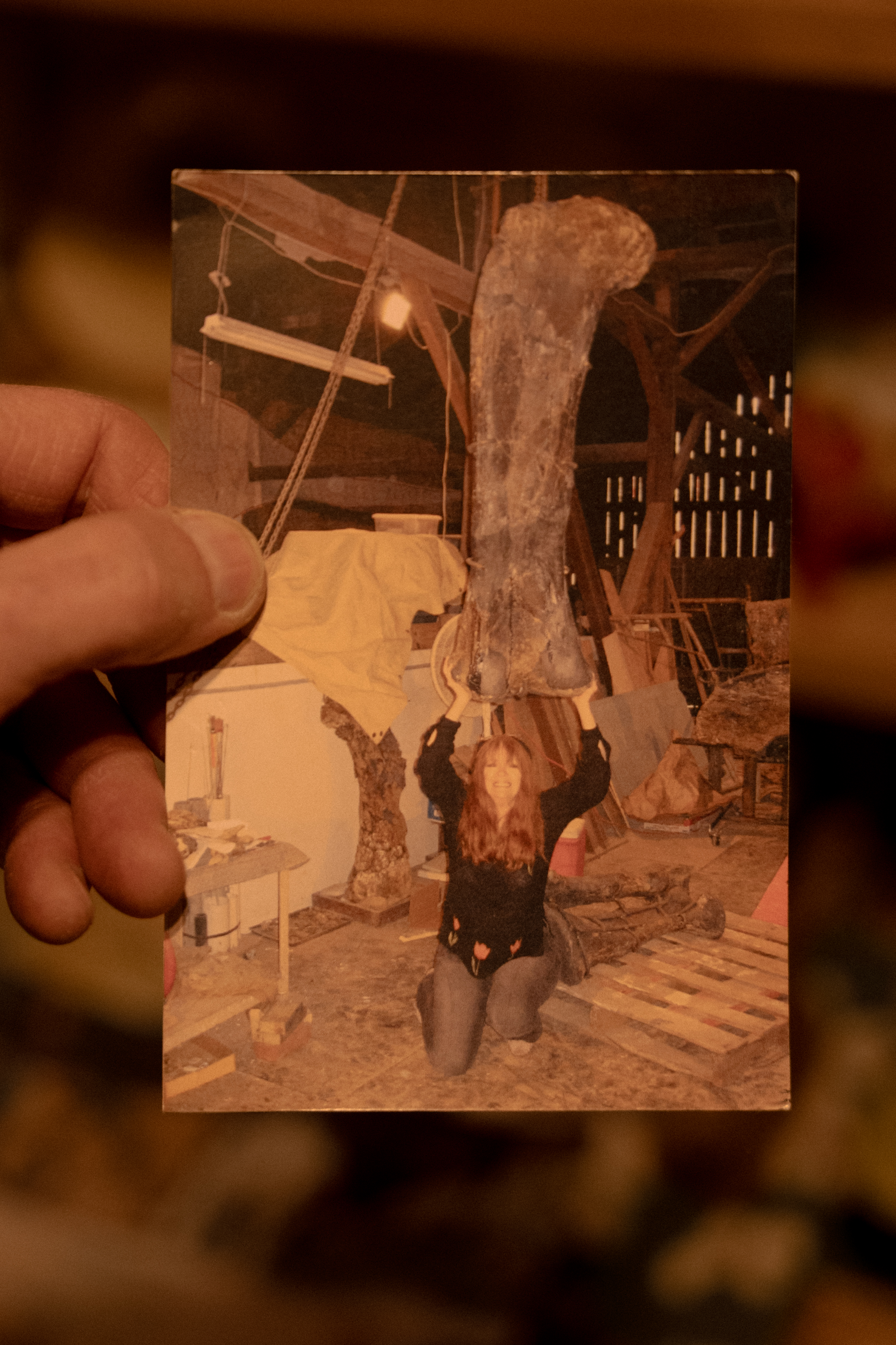 Barry James sostiene una foto de su esposa, April, con un femur gigante de un dinosaurio.