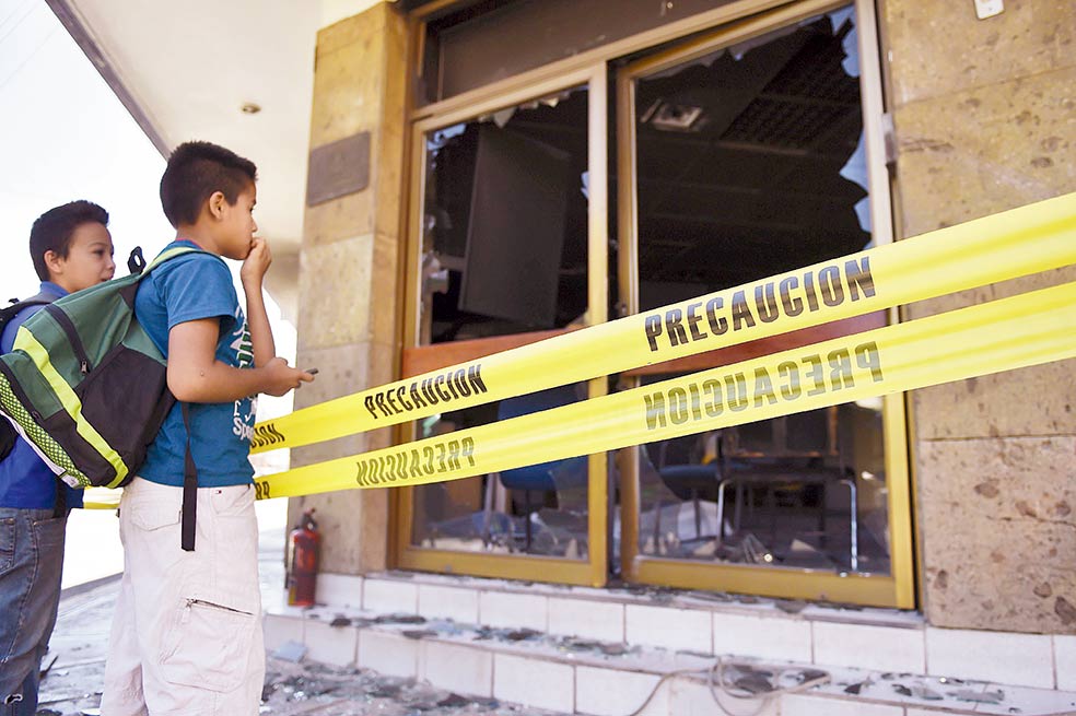 Dos niños miran las instalaciones del banco Banamex que fue quemado por hombres del CJNG. / AFP