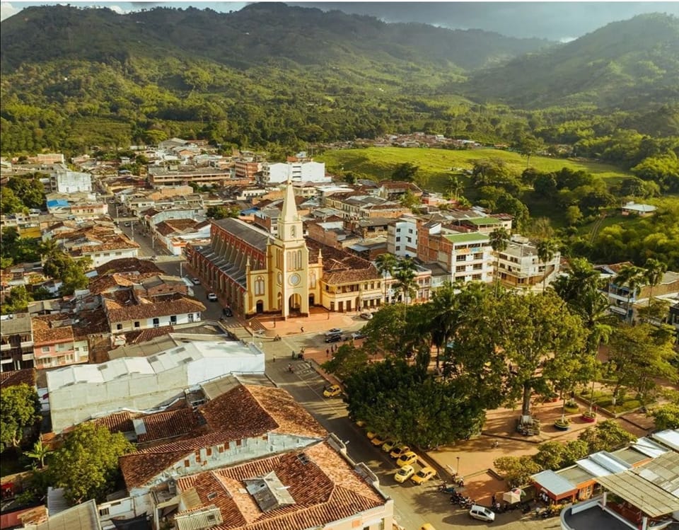 Caicedonia, conocida como la “Centinela del Valle”, tiene una historia que se remonta a tiempos prehispánicos, cuando estas tierras eran habitadas por la tribu Burila, reconocida por su carácter fuerte y su resistencia. Ubicado en el extremo oriental del Valle del Cauca, a más de 1.100 metros de altura, el municipio ofrece vistas privilegiadas sobre el valle y un entorno marcado por la vegetación y las heliconias. Hoy, además de su vocación agrícola, Caicedonia se presenta como un destino ideal para quienes buscan una experiencia rural auténtica dentro del Paisaje Cultural Cafetero. Sus fincas permiten conocer de cerca el proceso del café, mientras que espacios como el Parque Nacional de las Heliconias, la vereda Samaria o la Reserva Natural El Zaino ofrecen contacto directo con la naturaleza. A esto se suma una vida cultural activa, con eventos como el concurso nacional del bolero y el festival de música religiosa, así como atractivos como el Museo Arqueológico y los biomurales del municipio.