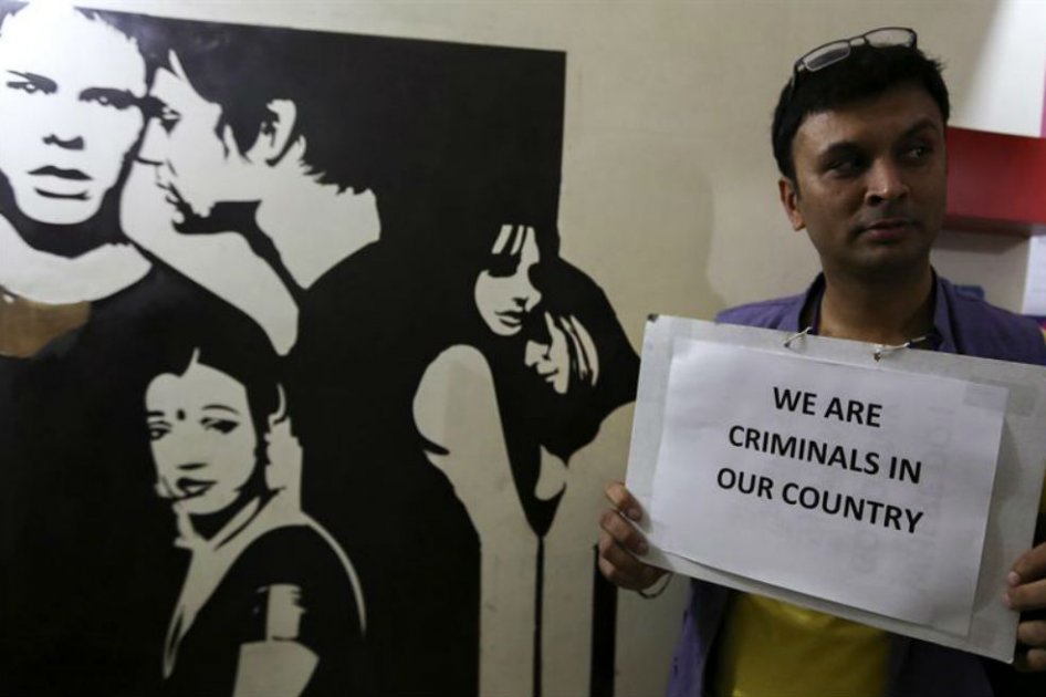Un activista sostiene una pancarta en la que se puede leer "En nuestro país somos criminales" mientras se suceden manifestaciones contra del veredicto del Tribunal Supremo en el que restableció la ilegalidad de las relaciones sexuales entre homosexuales, cuatro años después de que fueran despenalizadas